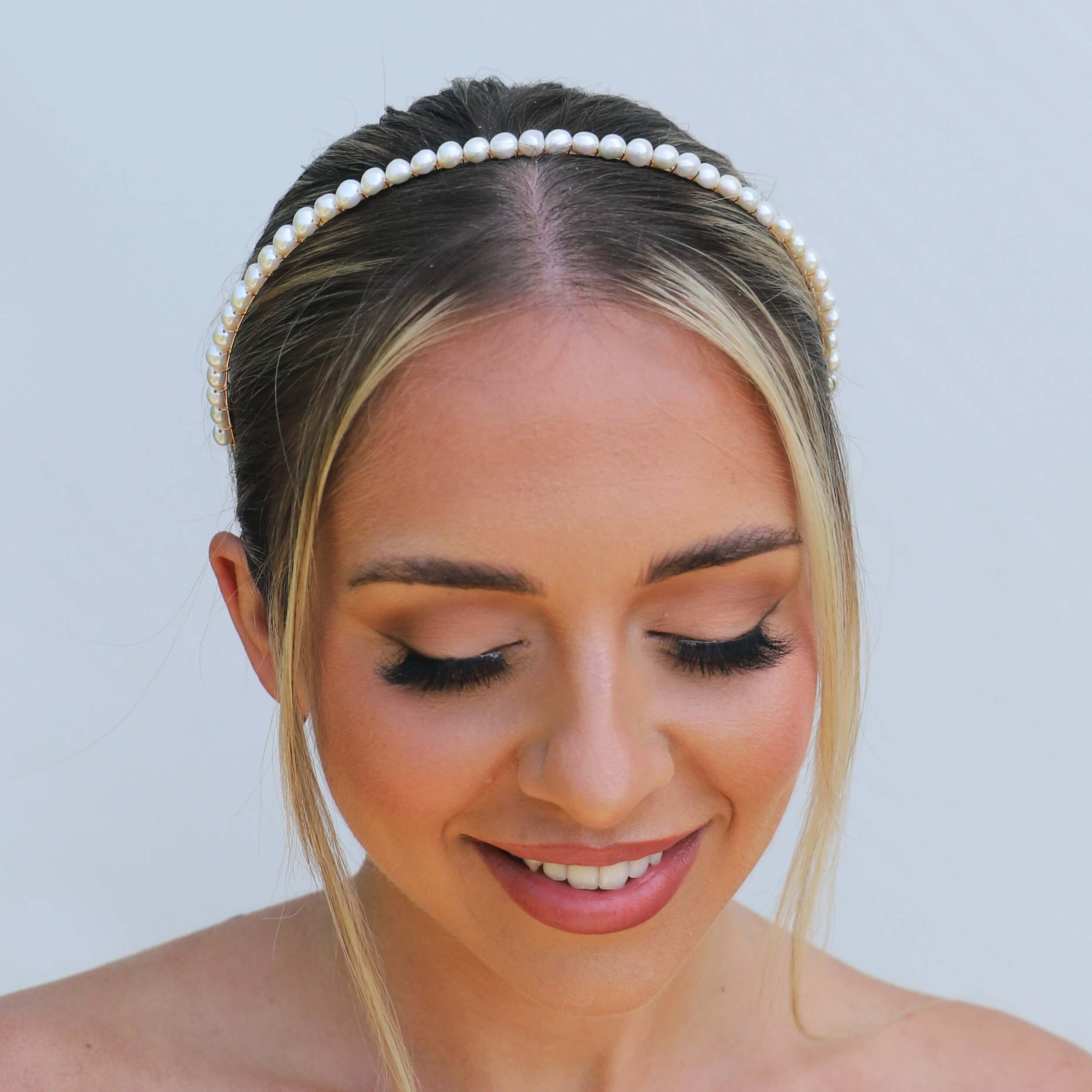 Headshot of bride with hair up wearing a pearl metal headband