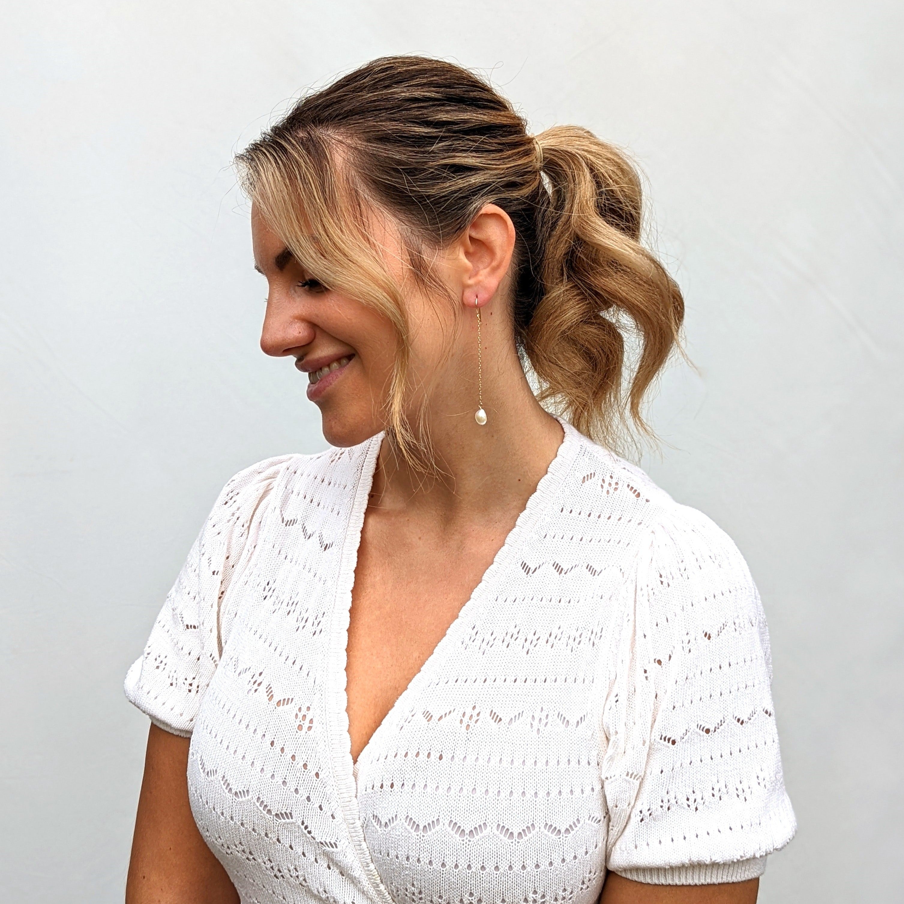 Model wearing white top and long pearl earring