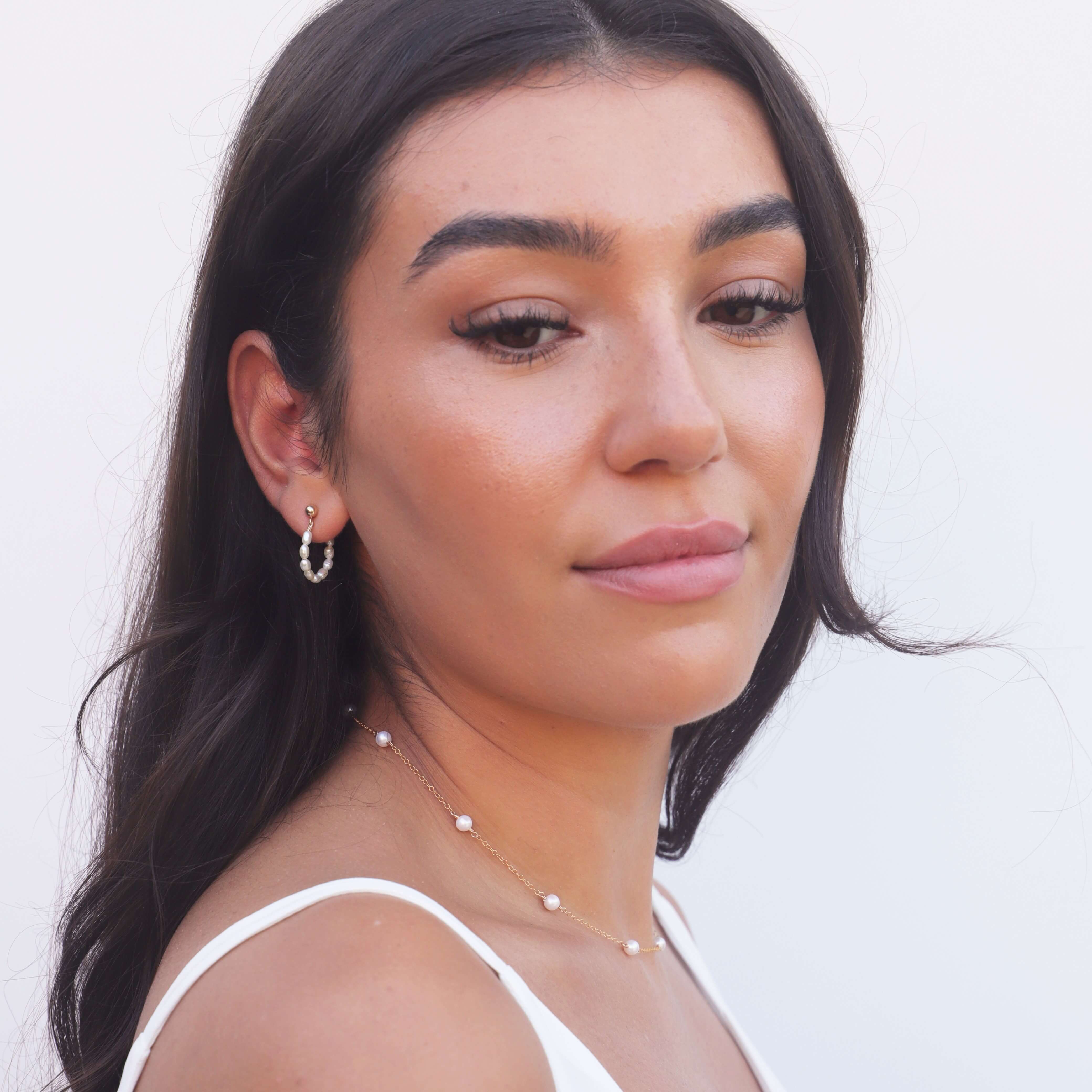 model with dark hair wearing gold filled pearl necklace