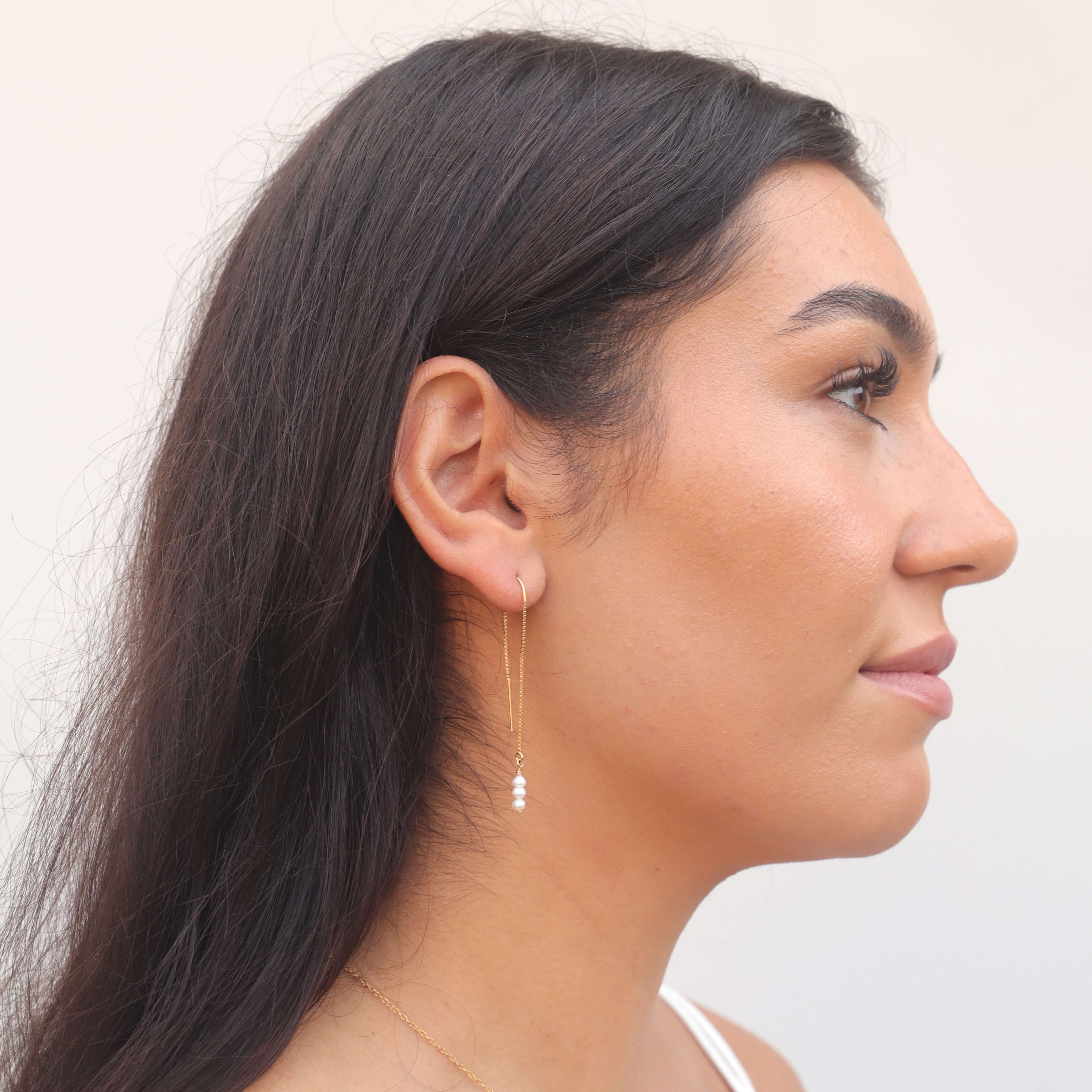 tiny pearl threader earrings in gold filled on model with dark hair