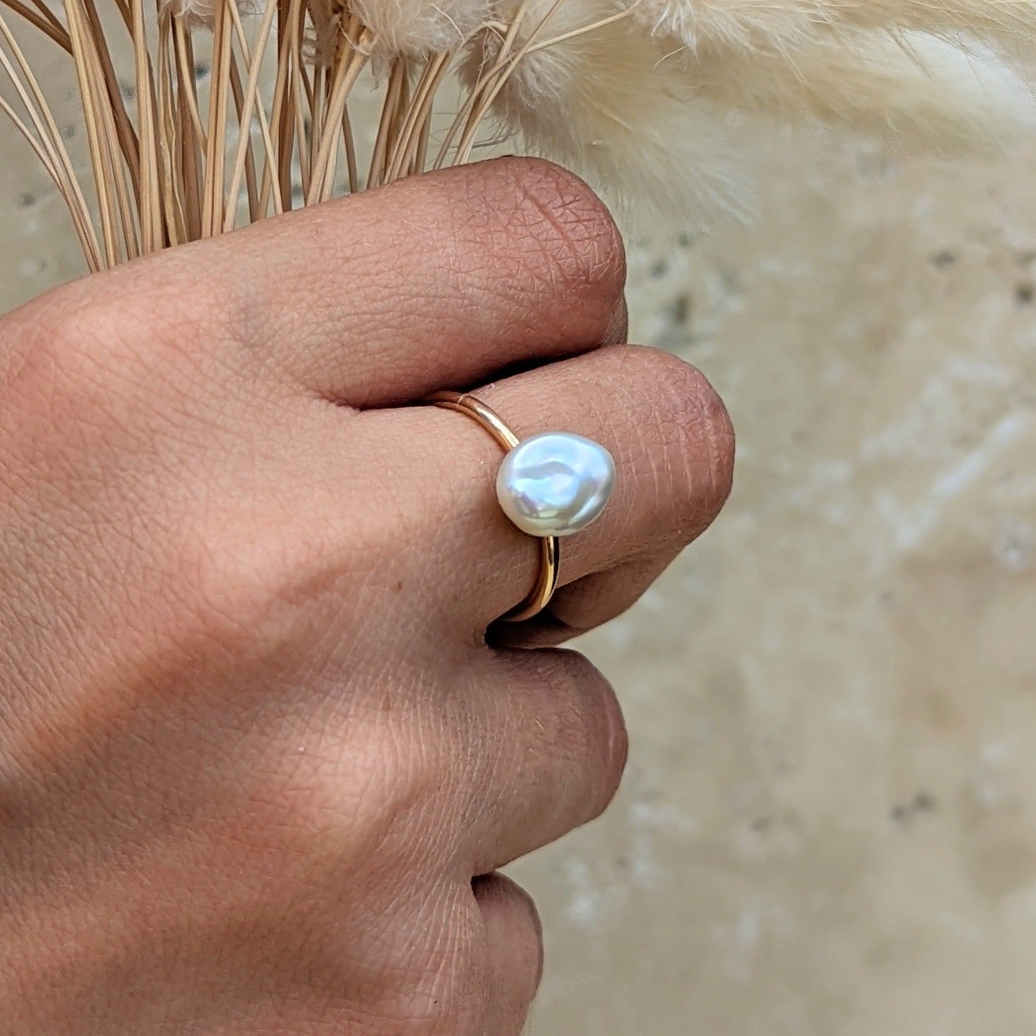Hand holding dried grass wearing gold baroque pearl ring