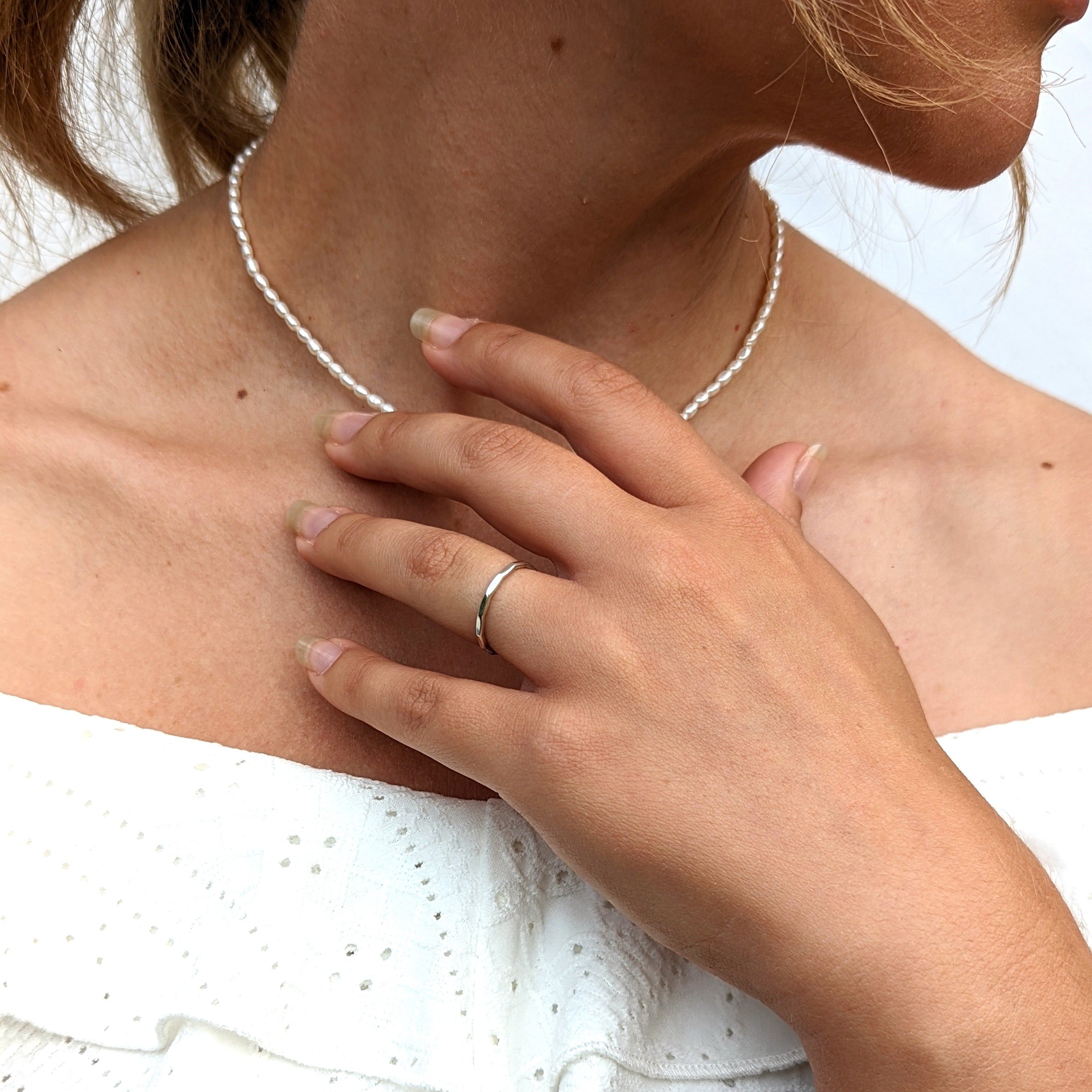 Model wearing pearl necklace and silver hammered ring