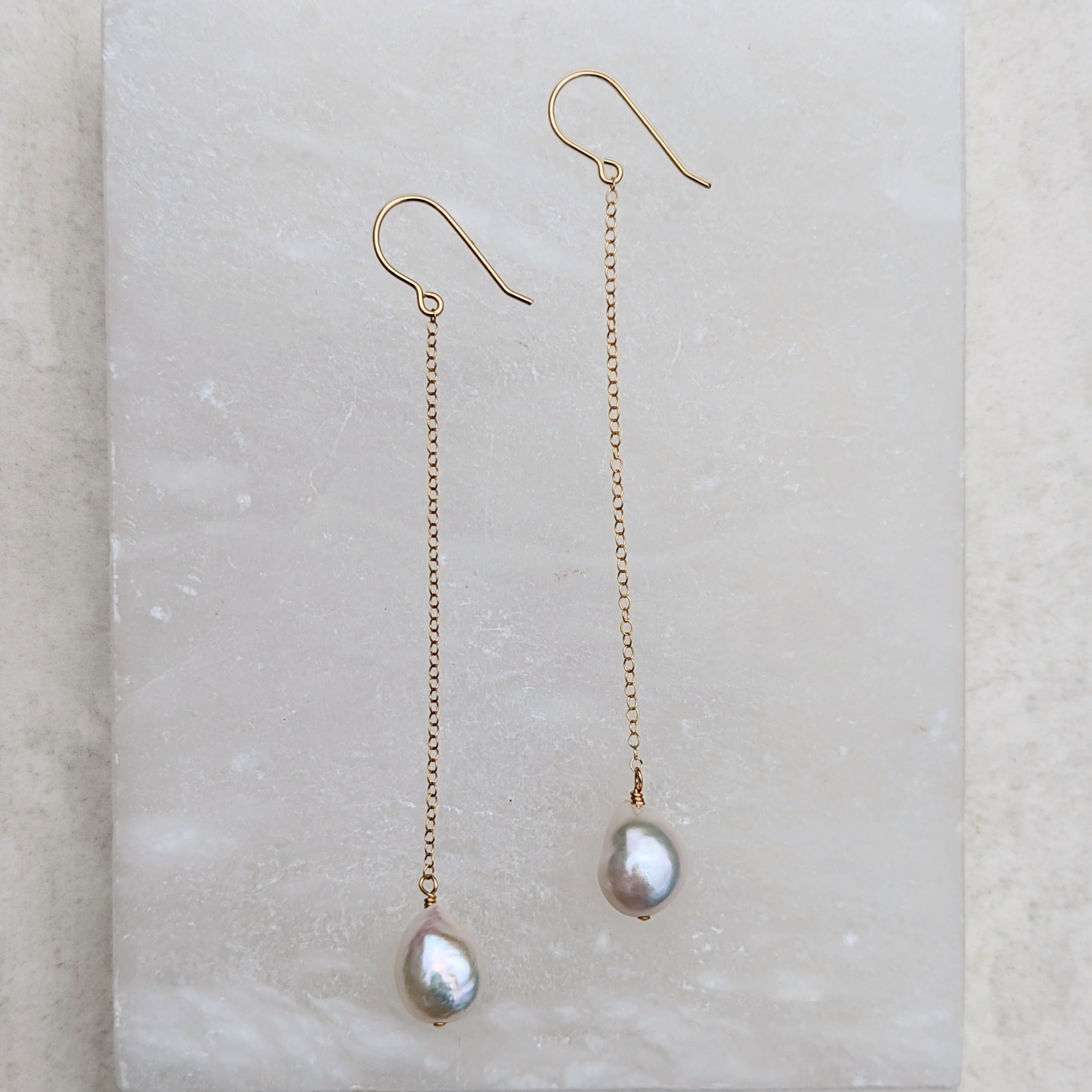 pair of long chain pearl earrings in gold