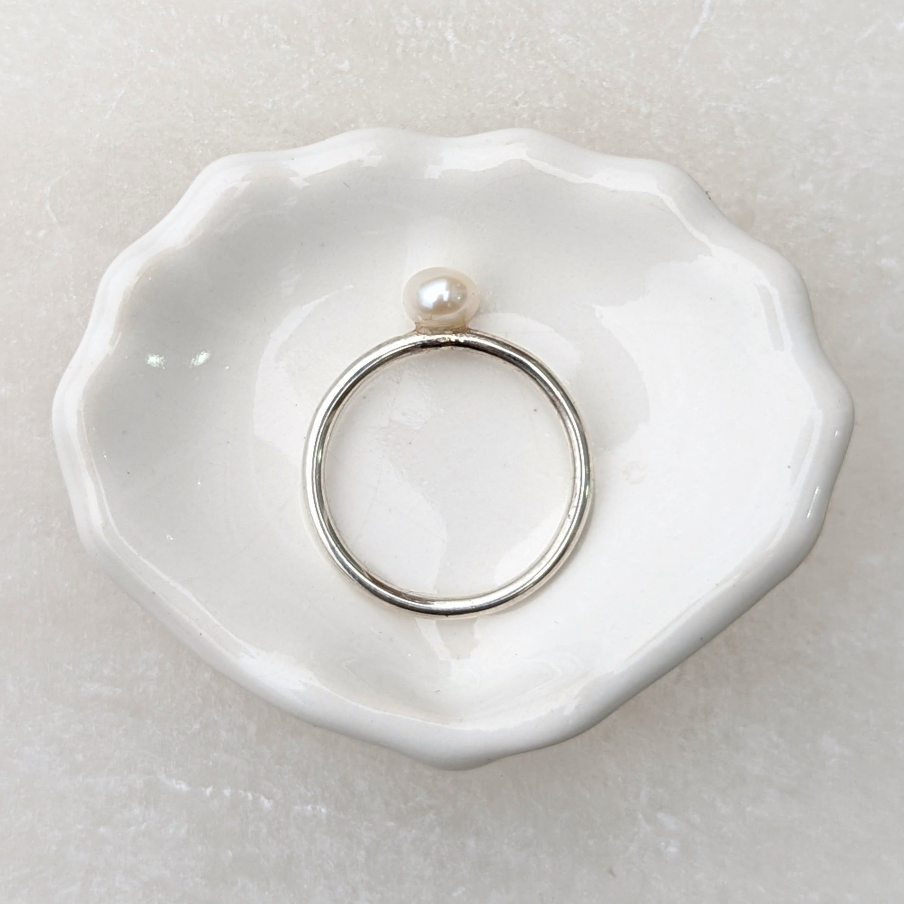 silver round pearl ring laid flat on trinket dish