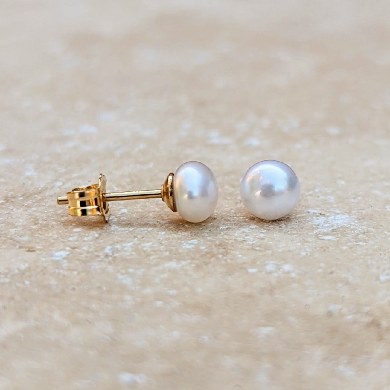 A pair of small button pearl stud earrings in gold filled