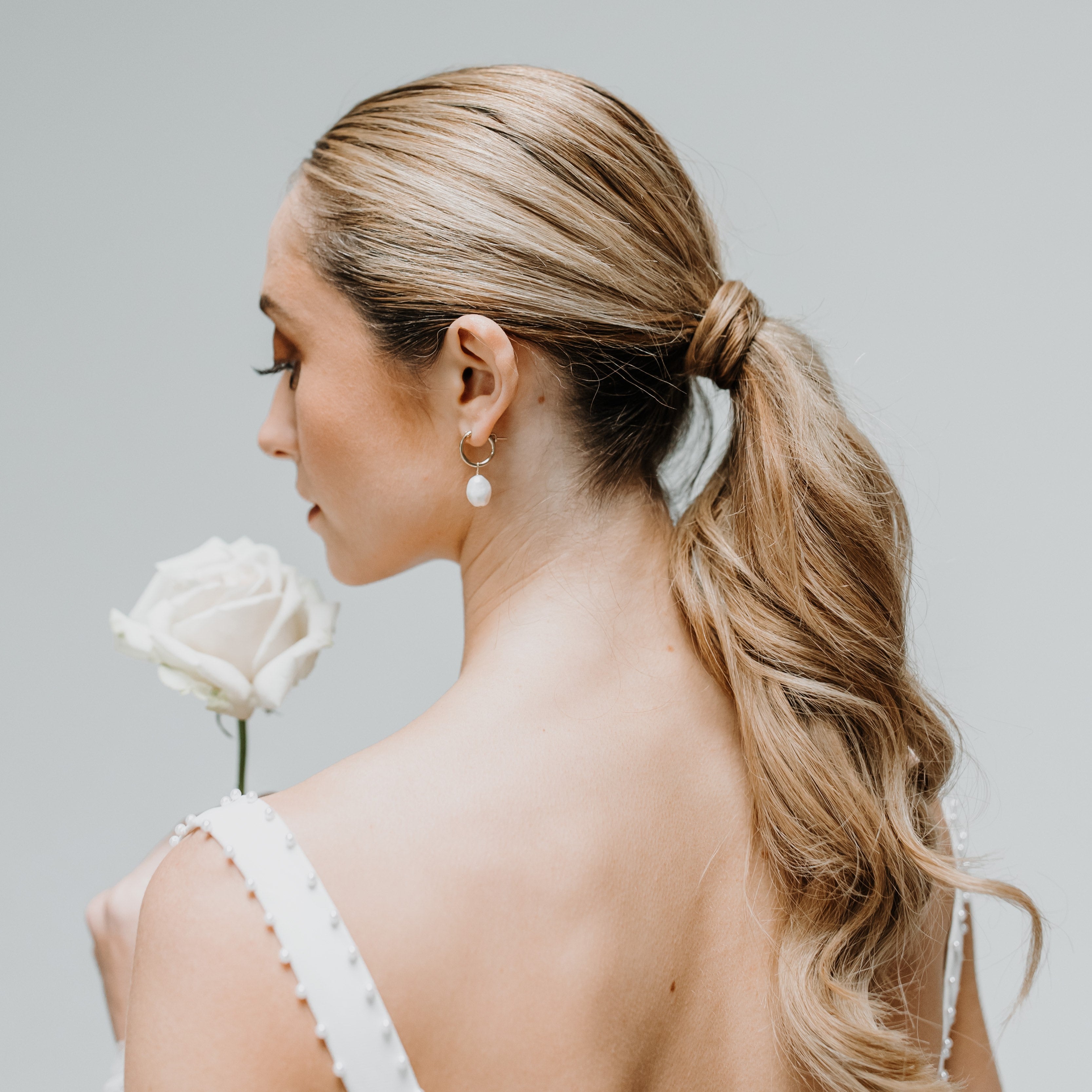 Bride with hair up wearing gold pearl hoop earrings