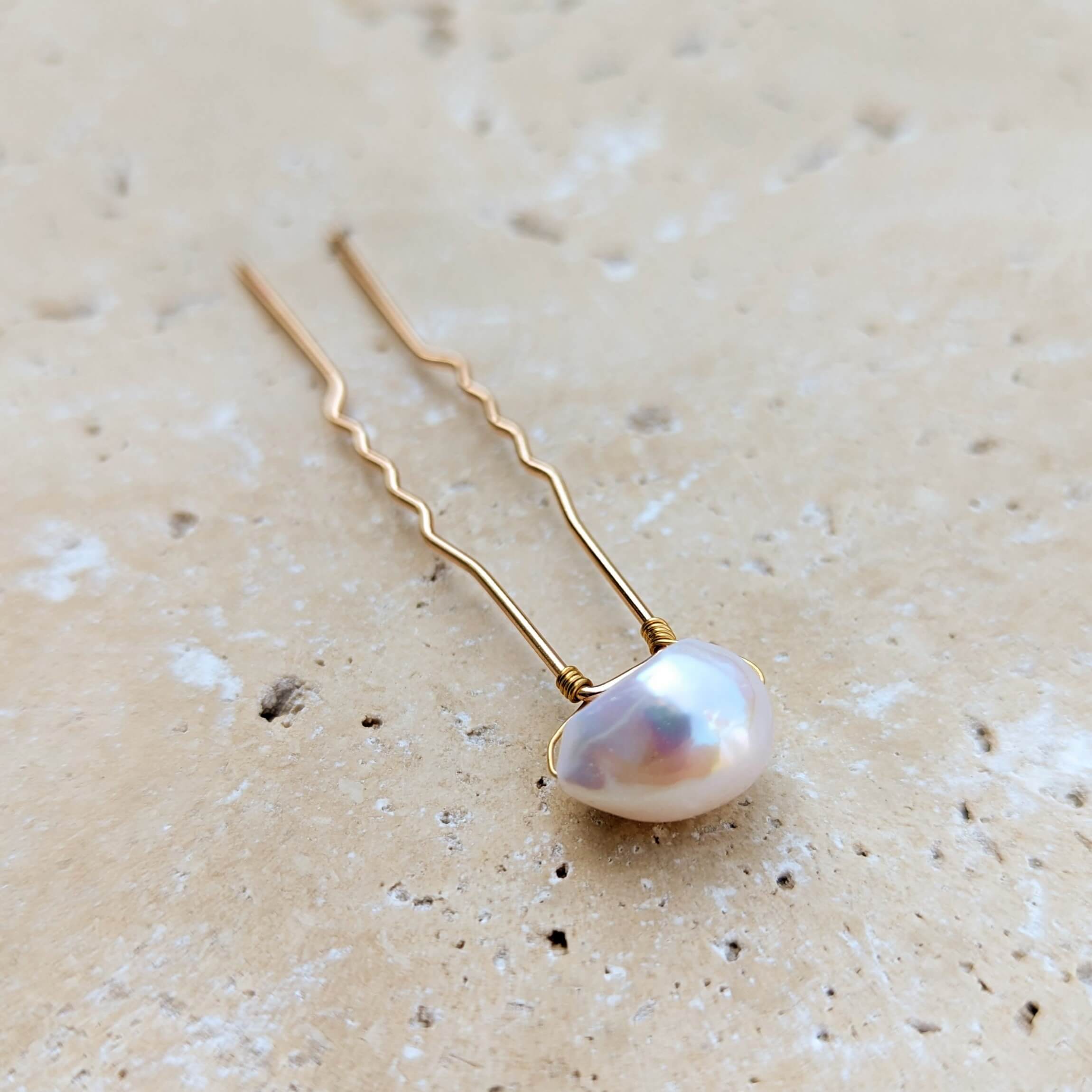 Single large baroque pearl on gold coloured hair pin