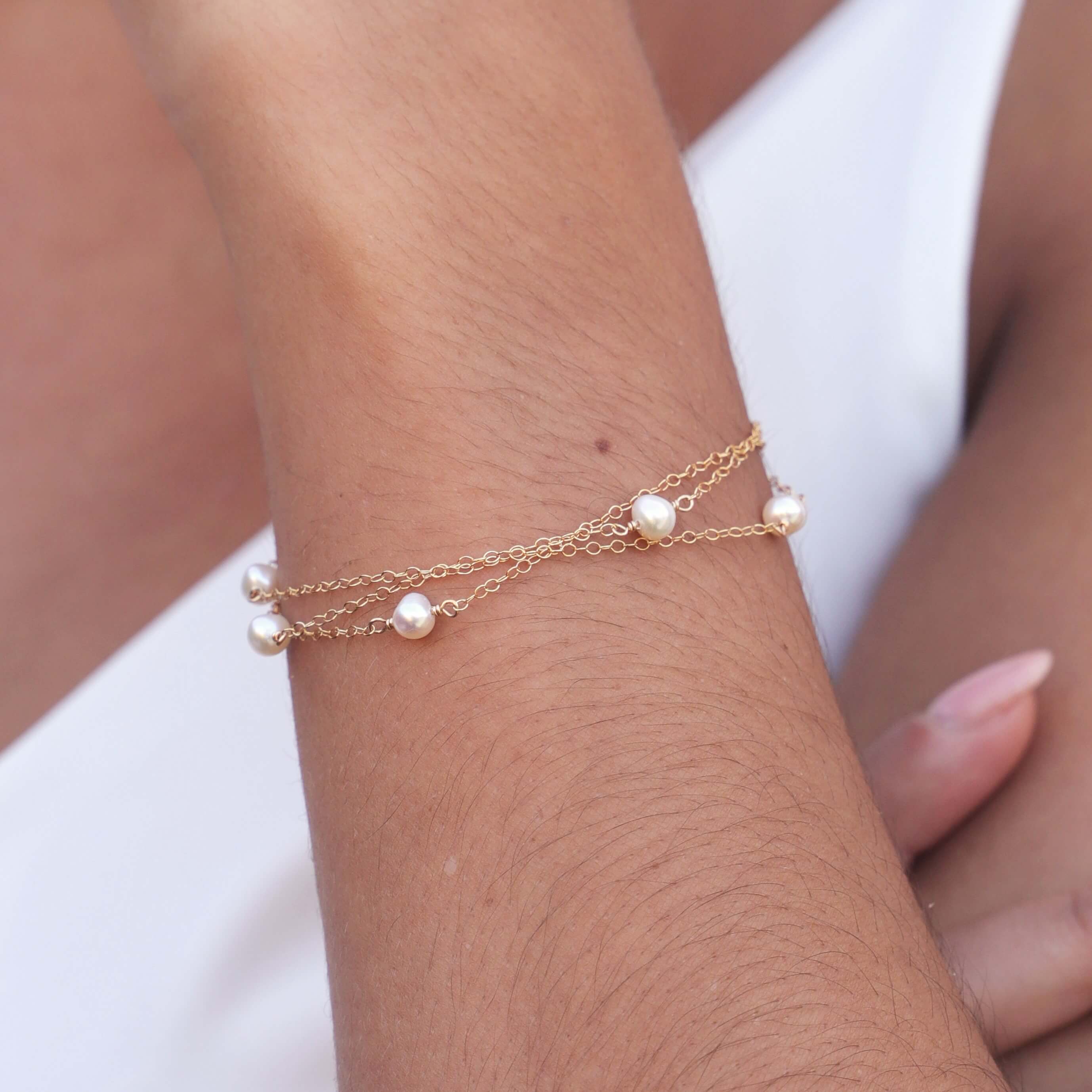 layered chain pearl bracelet in gold filled on model wrist close up