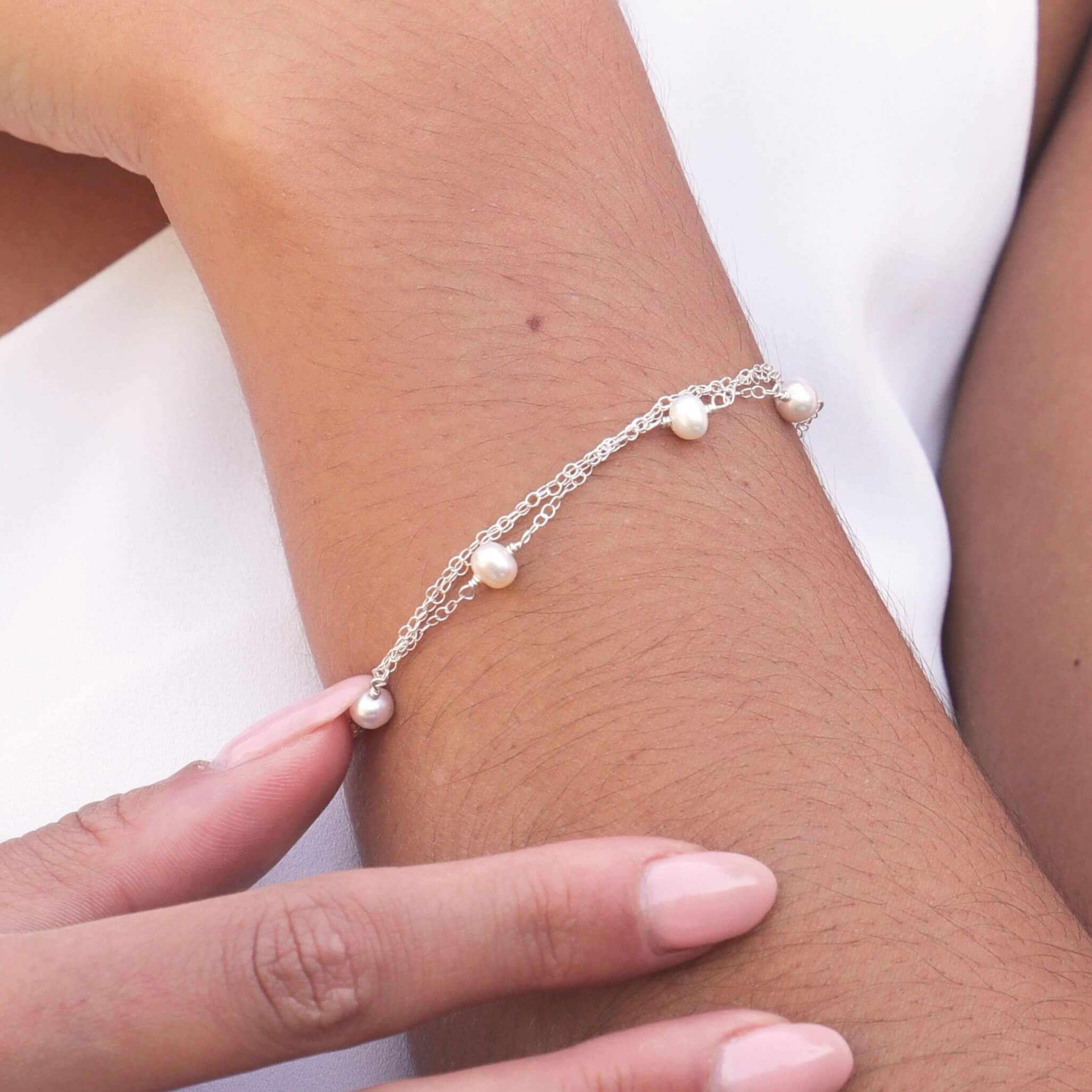 layered chain pearl bracelet in sterling silver close up on model wrist