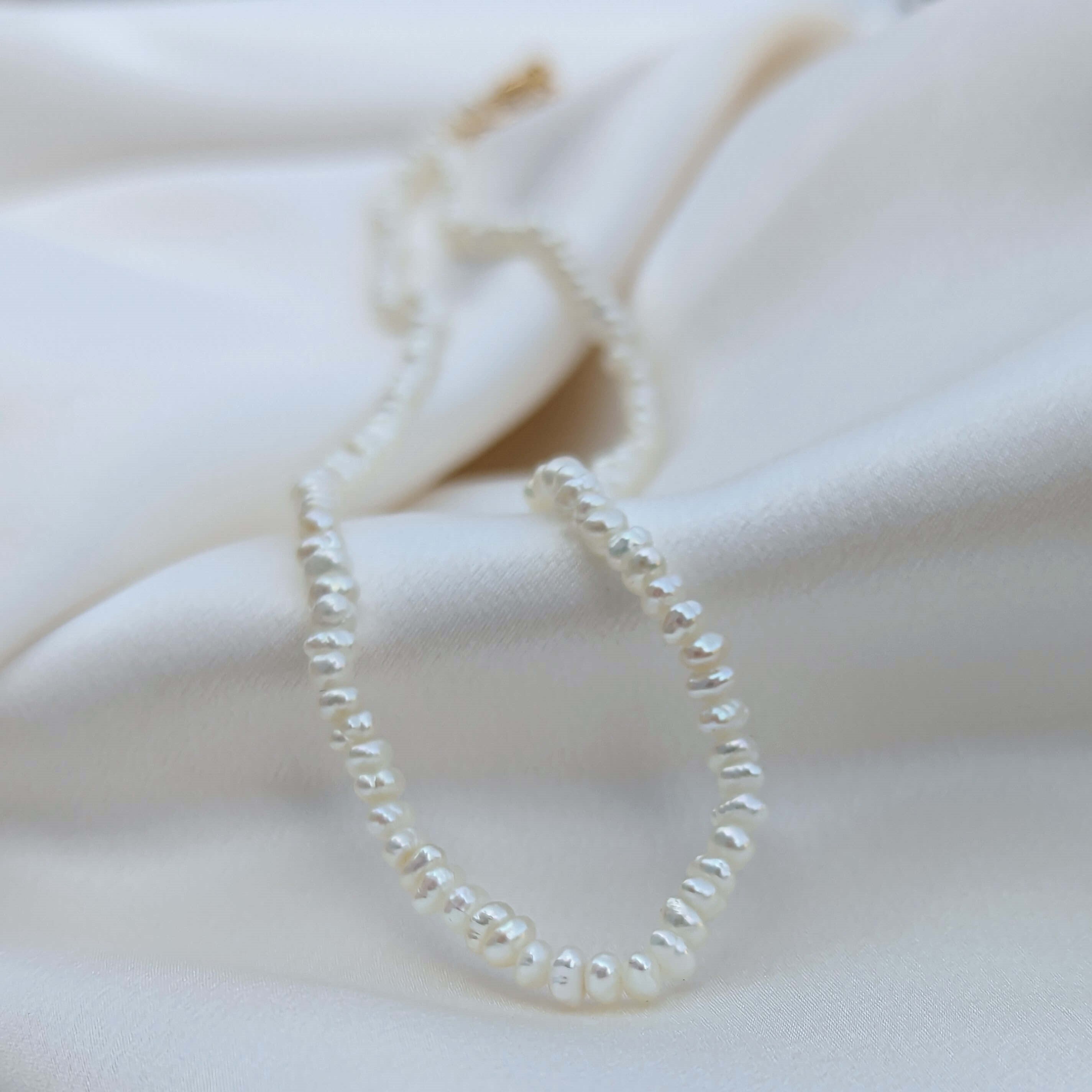 mini freshwater pearl necklace on silk background