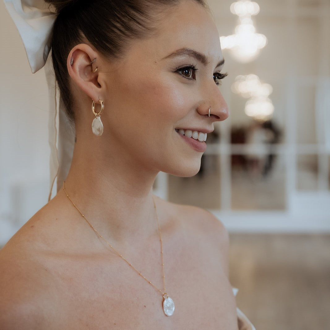 Close up shot of model wearing petal pearl hoop earrings