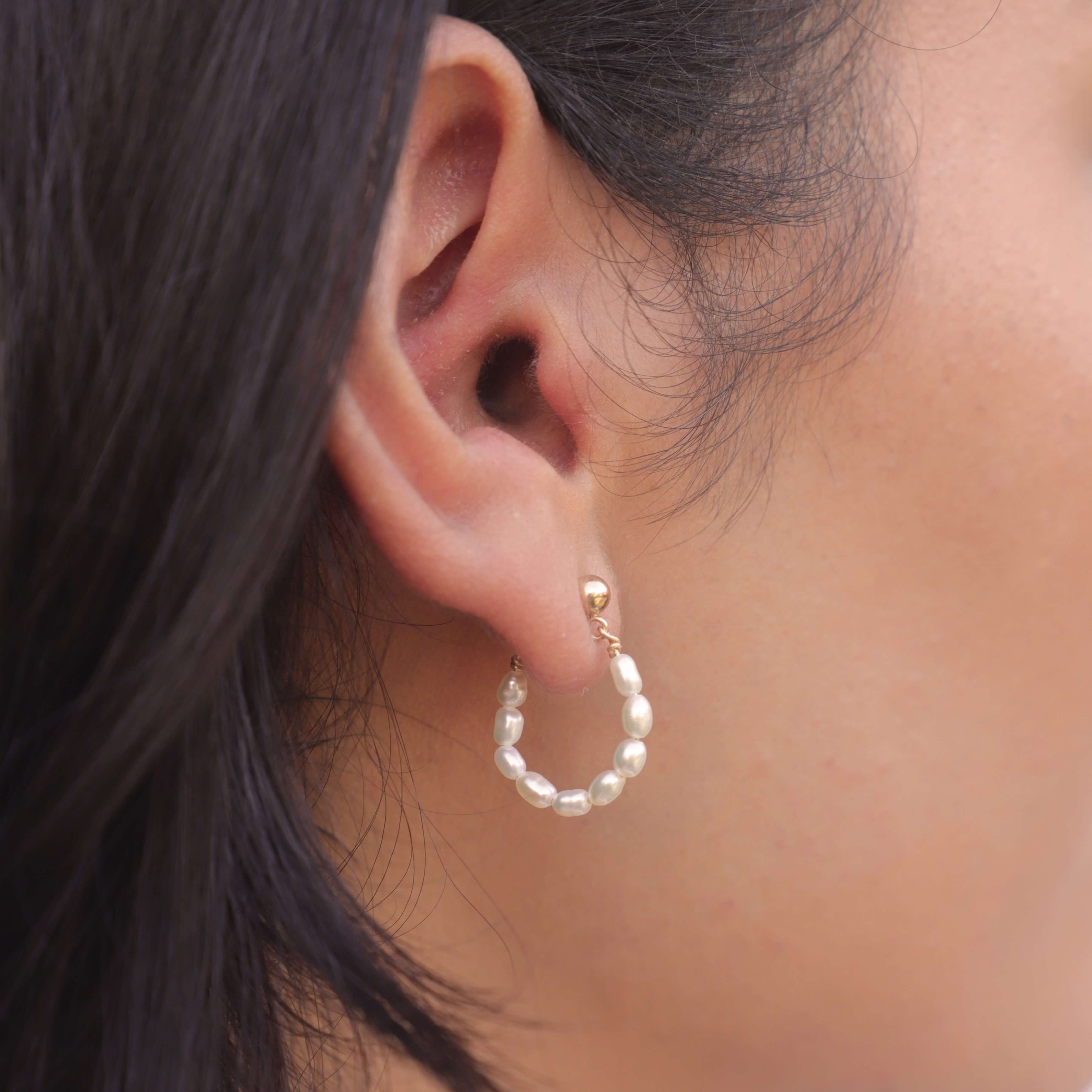 side view of model wearing pearl hoop earrings in gold filled