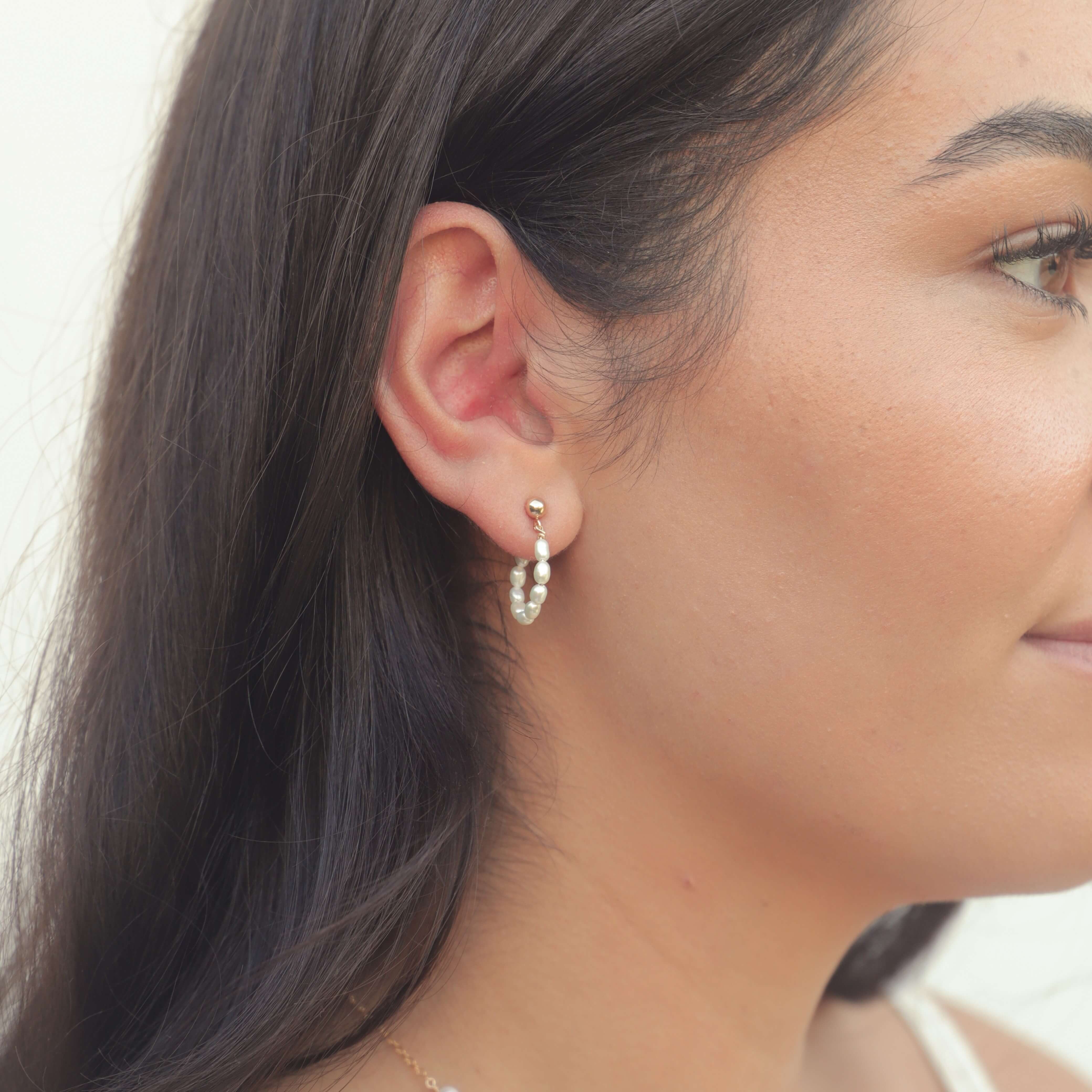 model with dark hair wearing seed pearl hoop earrings in gold filled