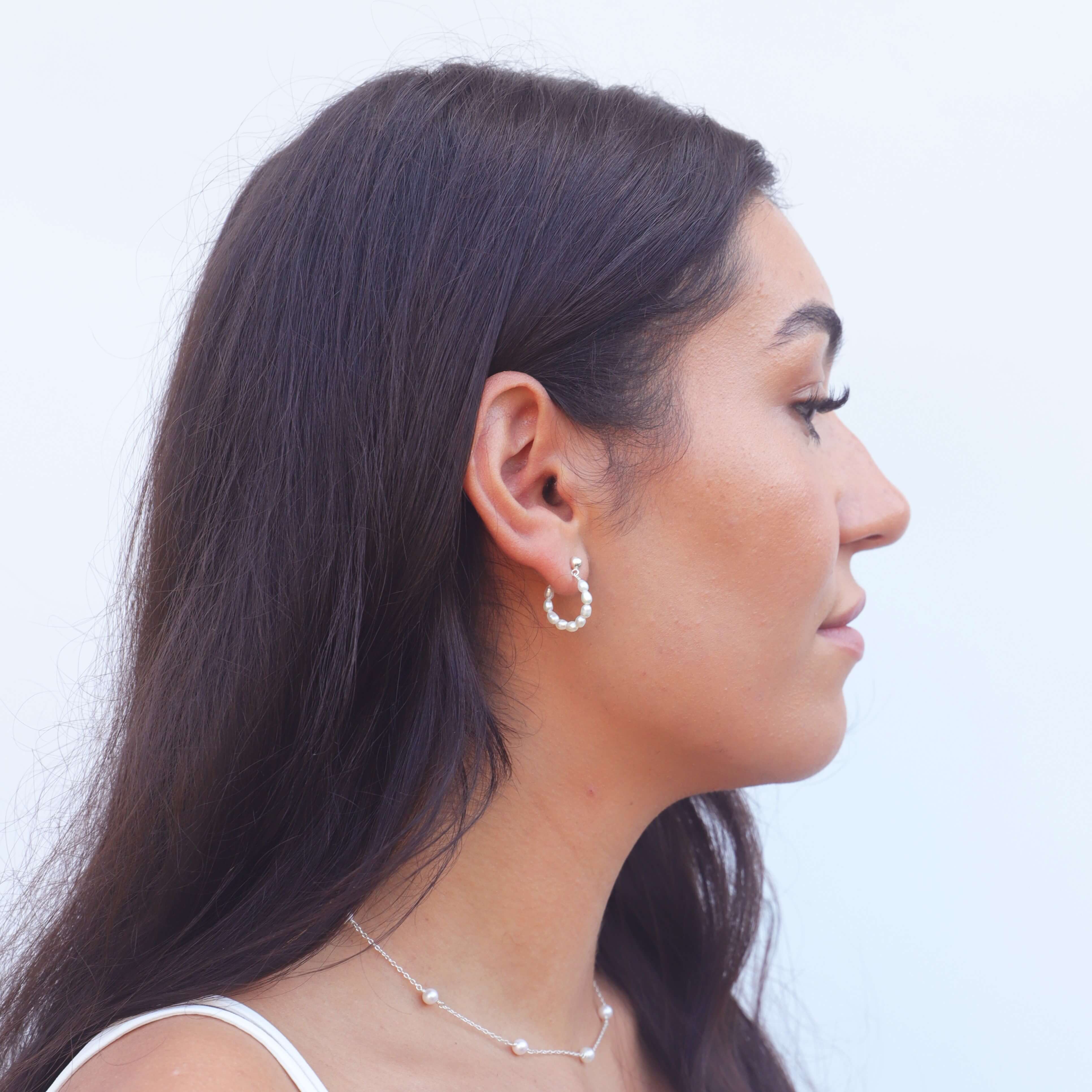 model with dark hair wearing seed pearl hoop earrings