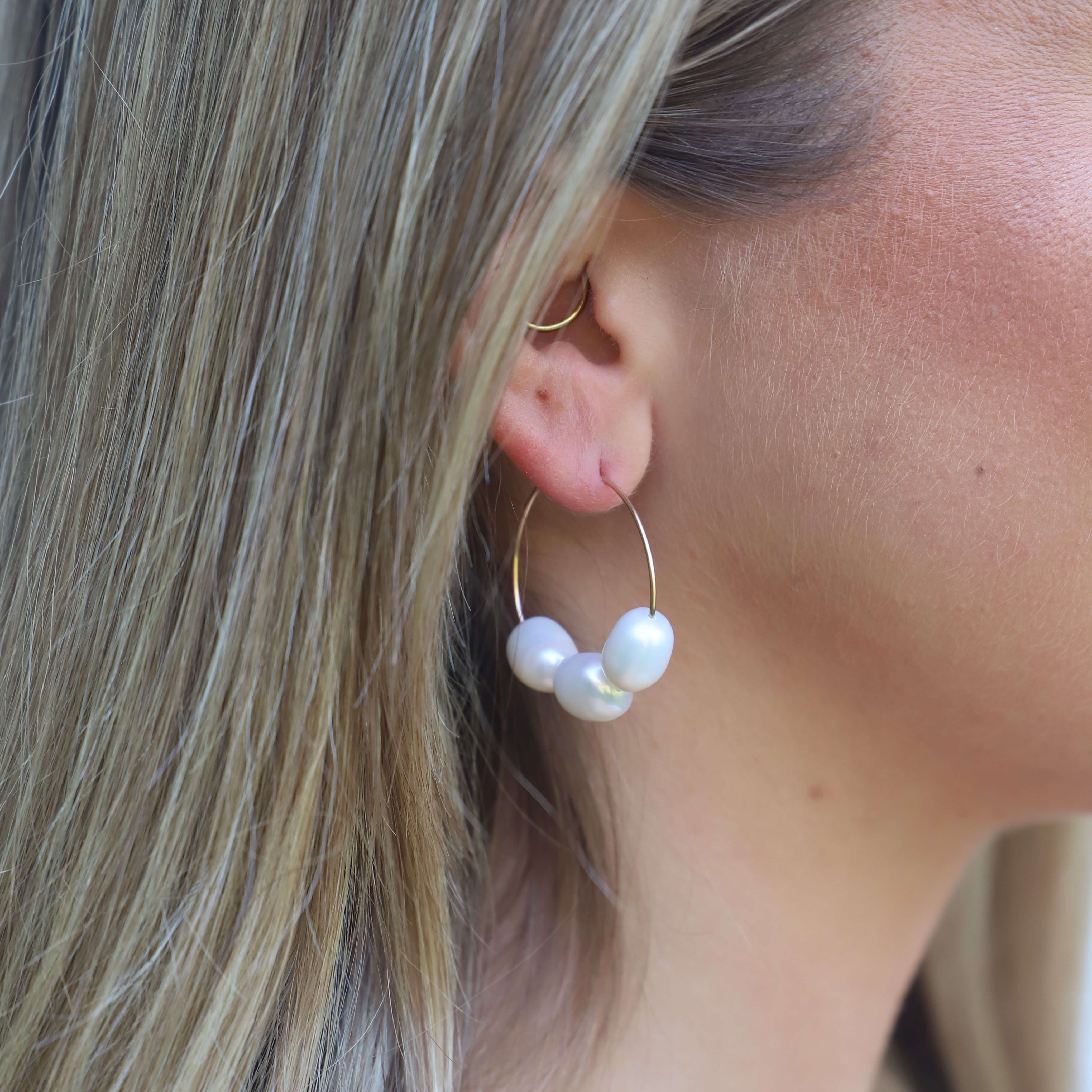 close up of three baroque pearls on wire hoop earring on model