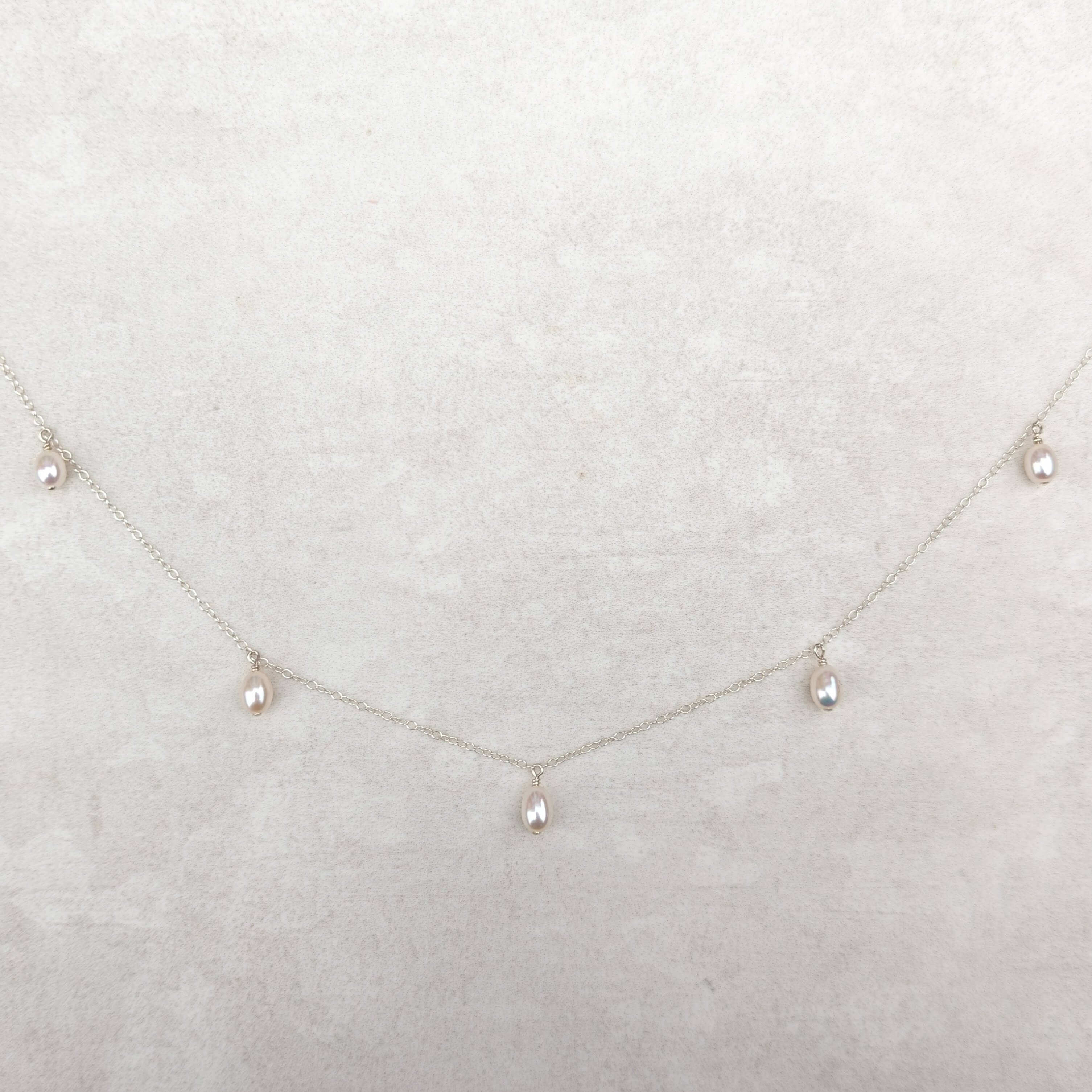 five small pearl pendants on a thin silver chain necklace