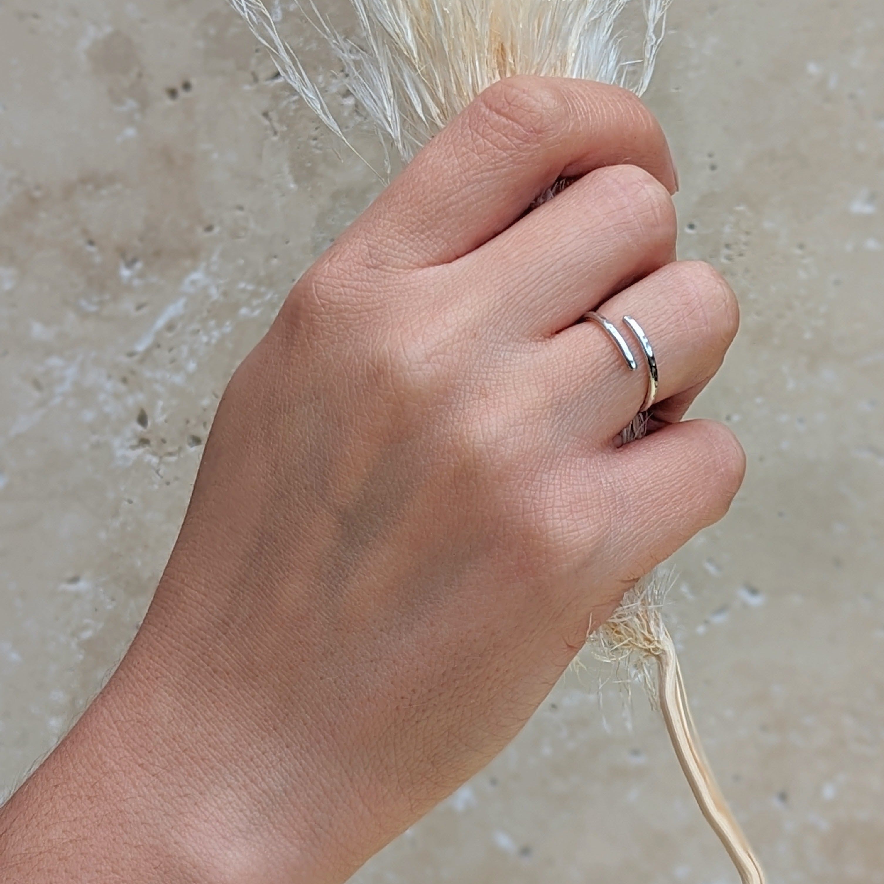 Hand holding dried floral wearing a hammered silver adjustable ring