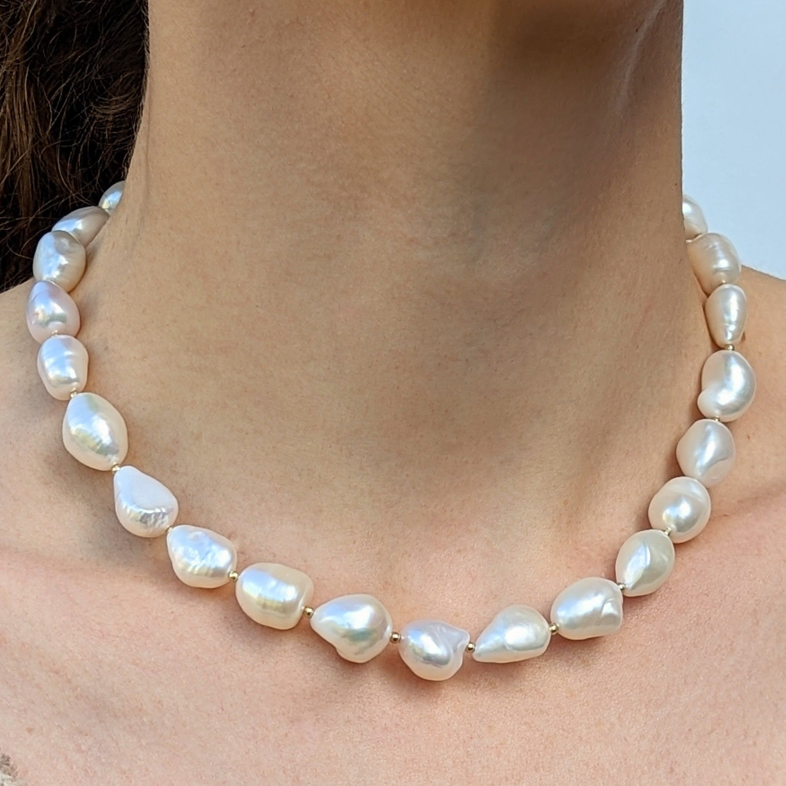 Neck wearing irregular shaped pearl and gold bead necklace