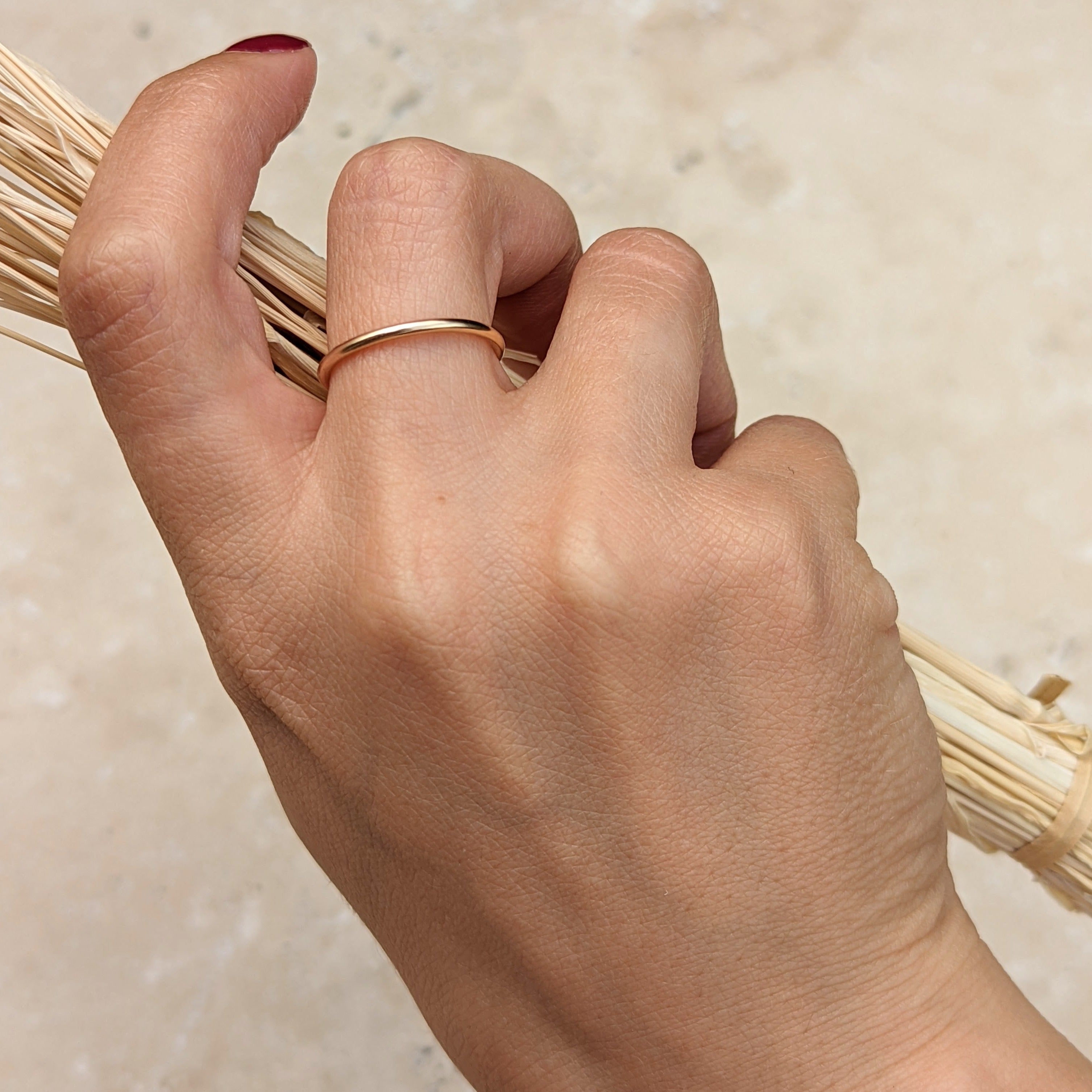 Hand holding dried grass and wearing a plain smooth slim gold filled ring