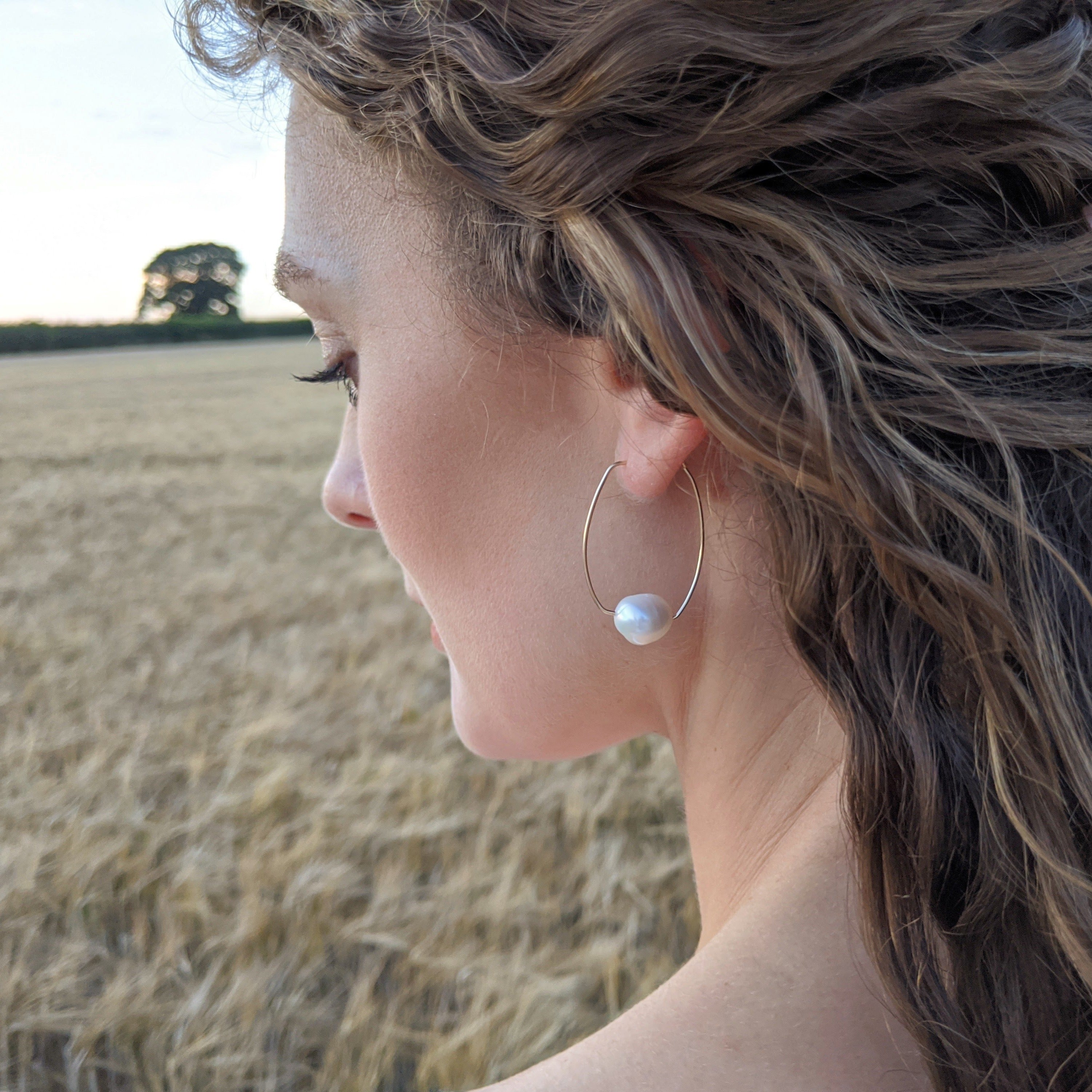 woman with gold pearl hoop earring