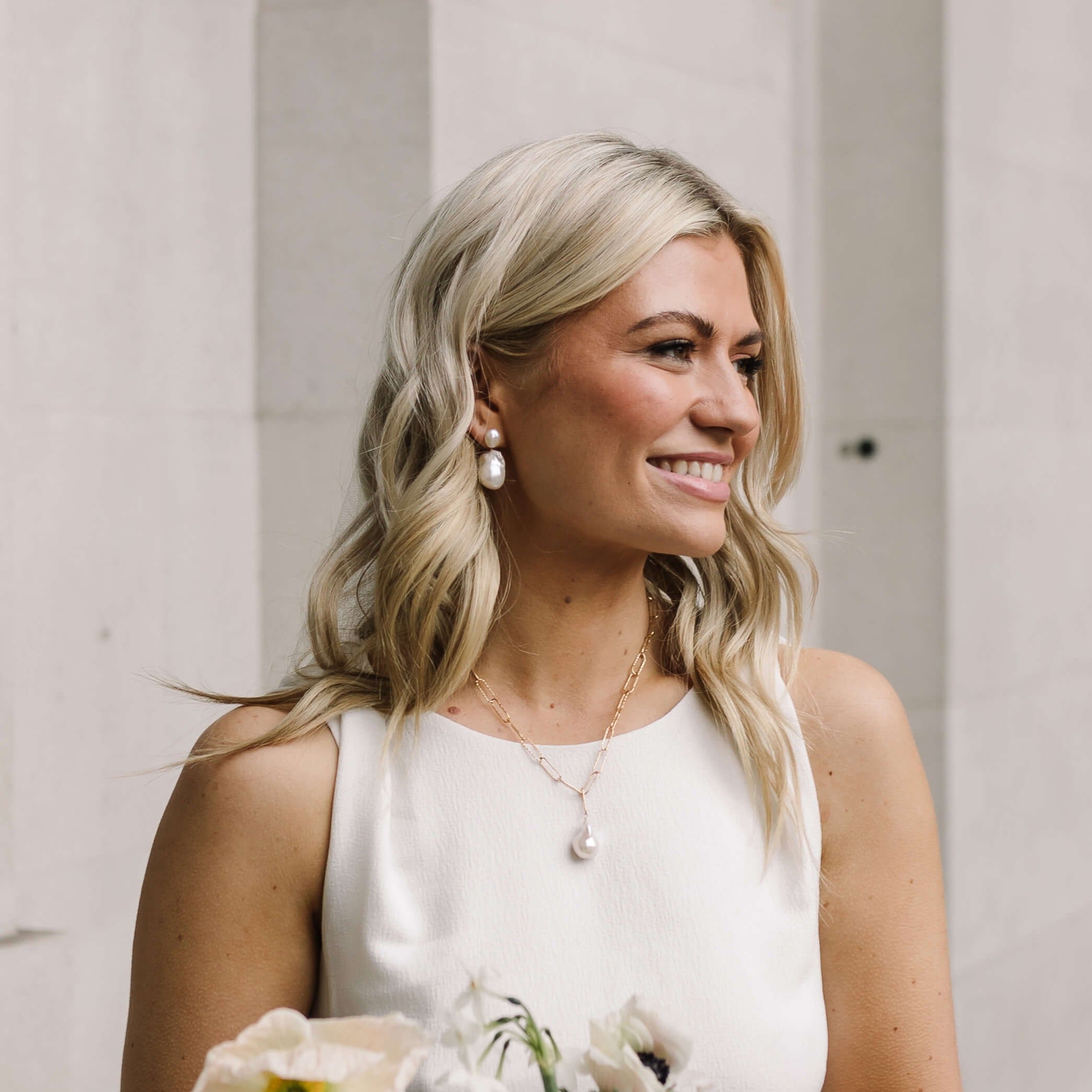 model wearing large baroque pearl earrings and necklace and white dress