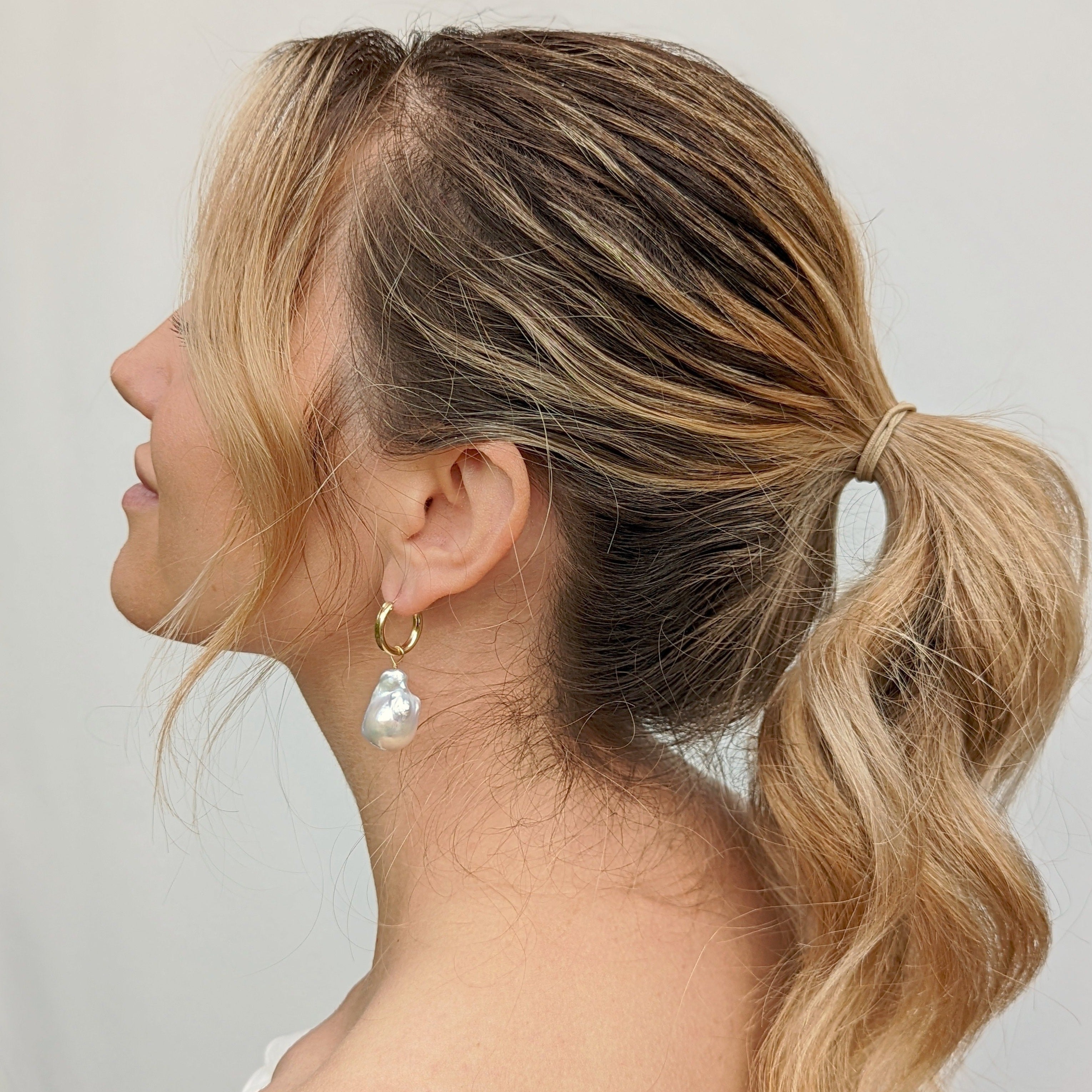 Model wearing large baroque pearl gold hoop earrings