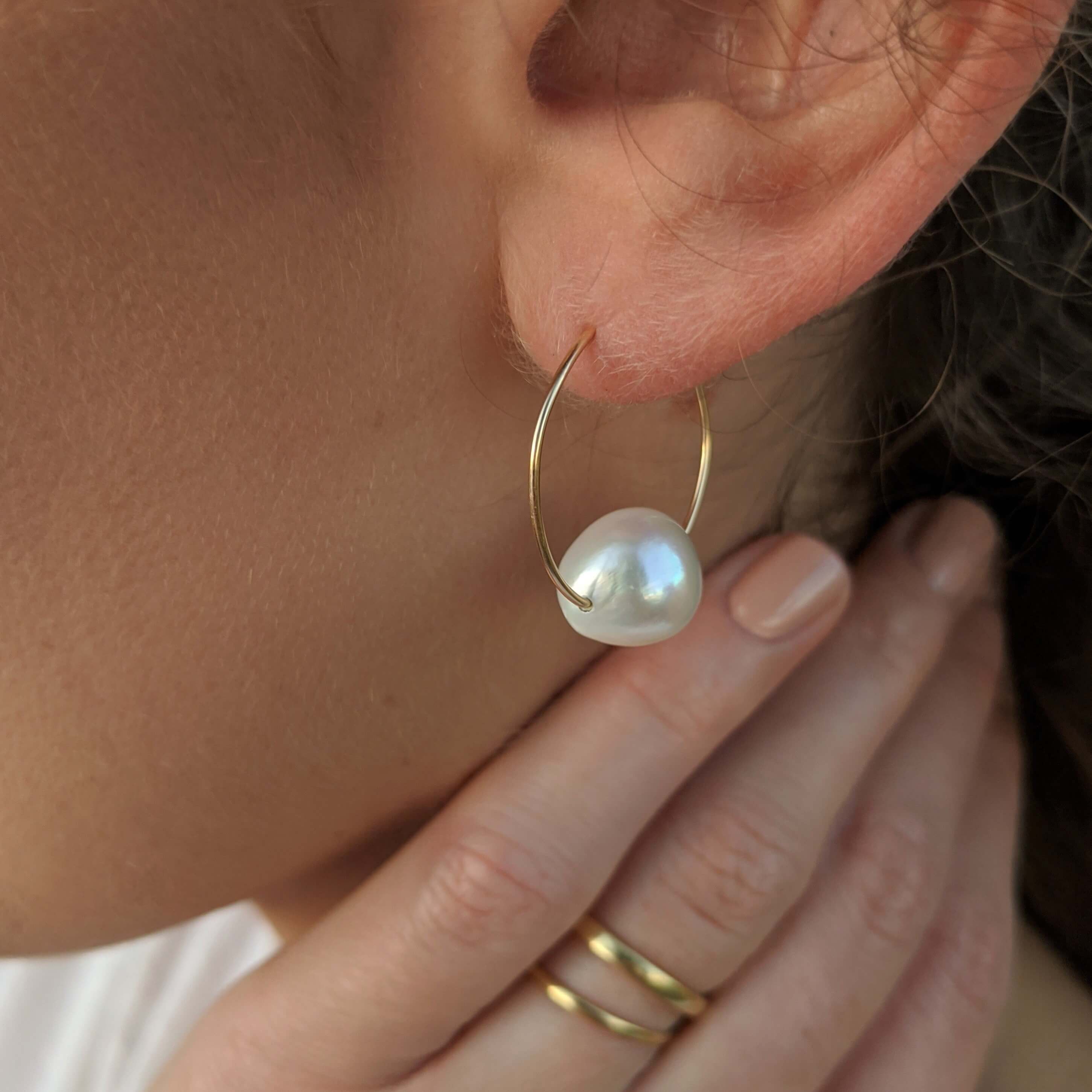 large pearl wire hoop earrings with single large pearl on model close up
