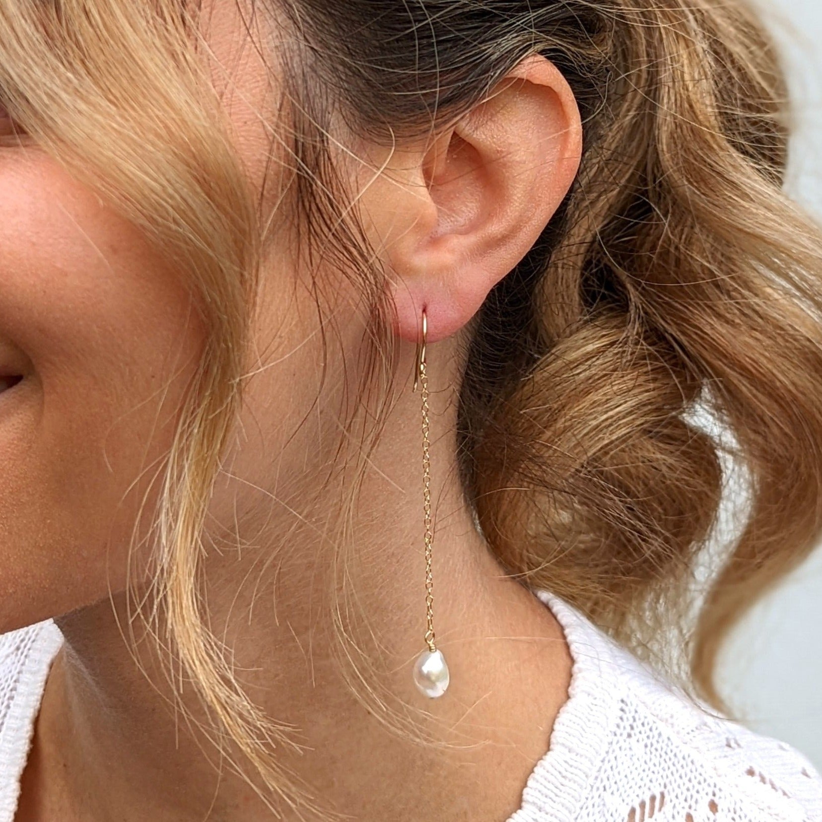 Closeup of models ear with long chain pearl earring