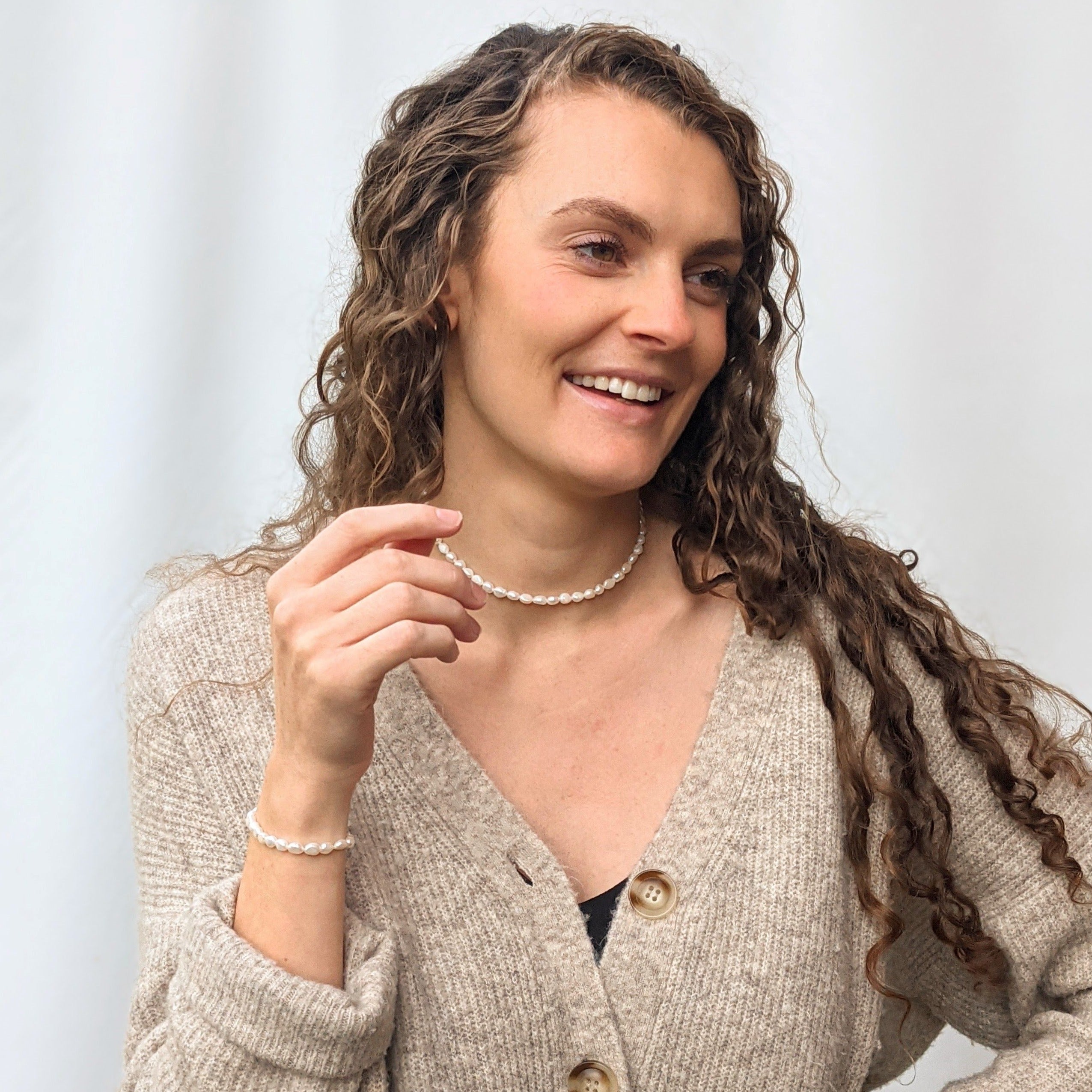 Model wearing a pearl choker necklace and a small baroque irregular seed bracelet