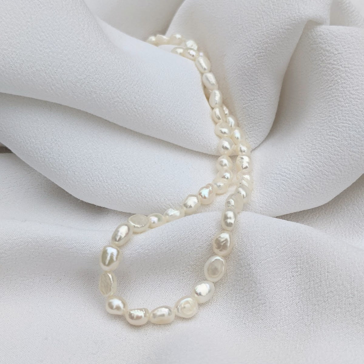 Irregular baroque pearl necklace on soft white fabric