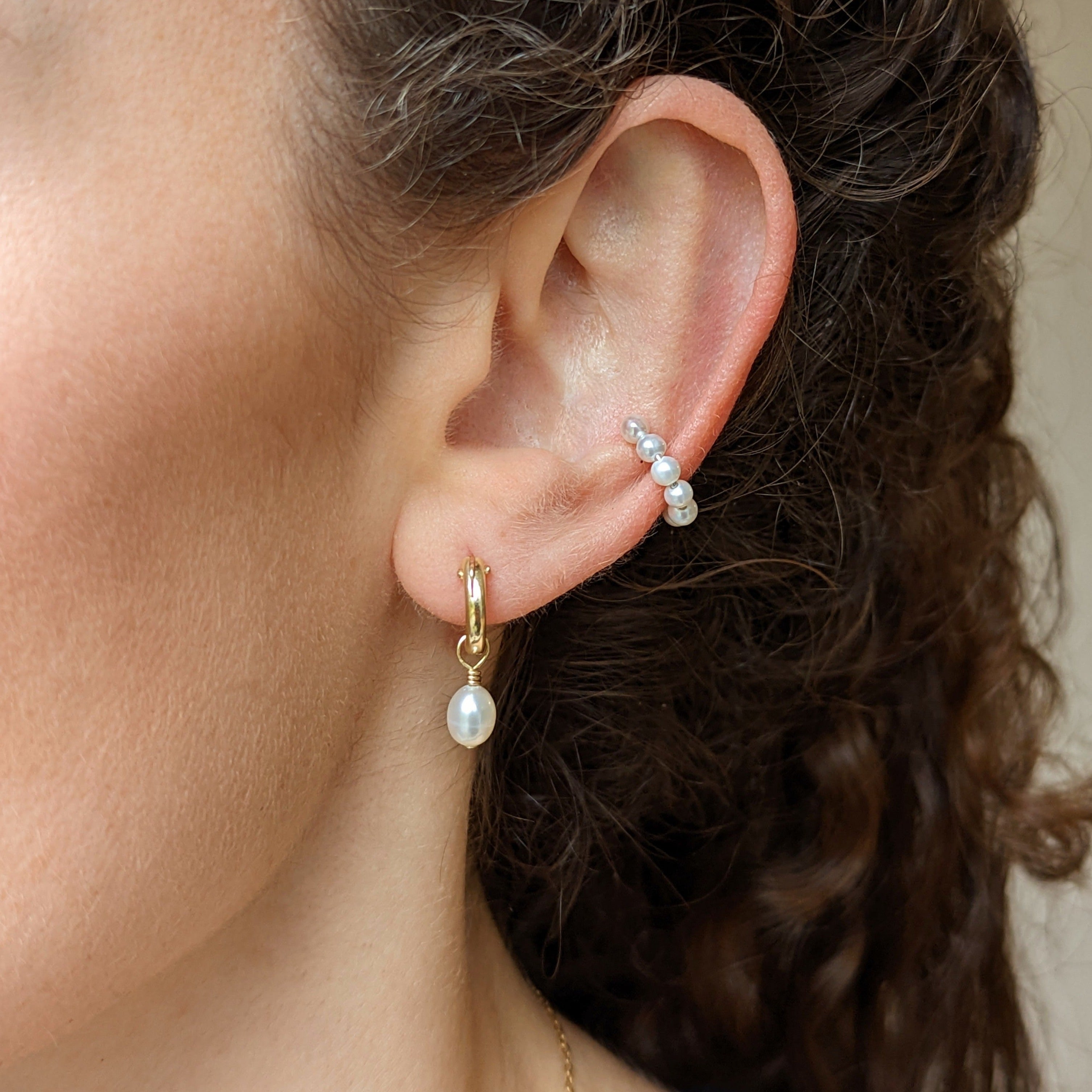 Closeup of ear with gold pearl hoop earring and pearl ear cuff