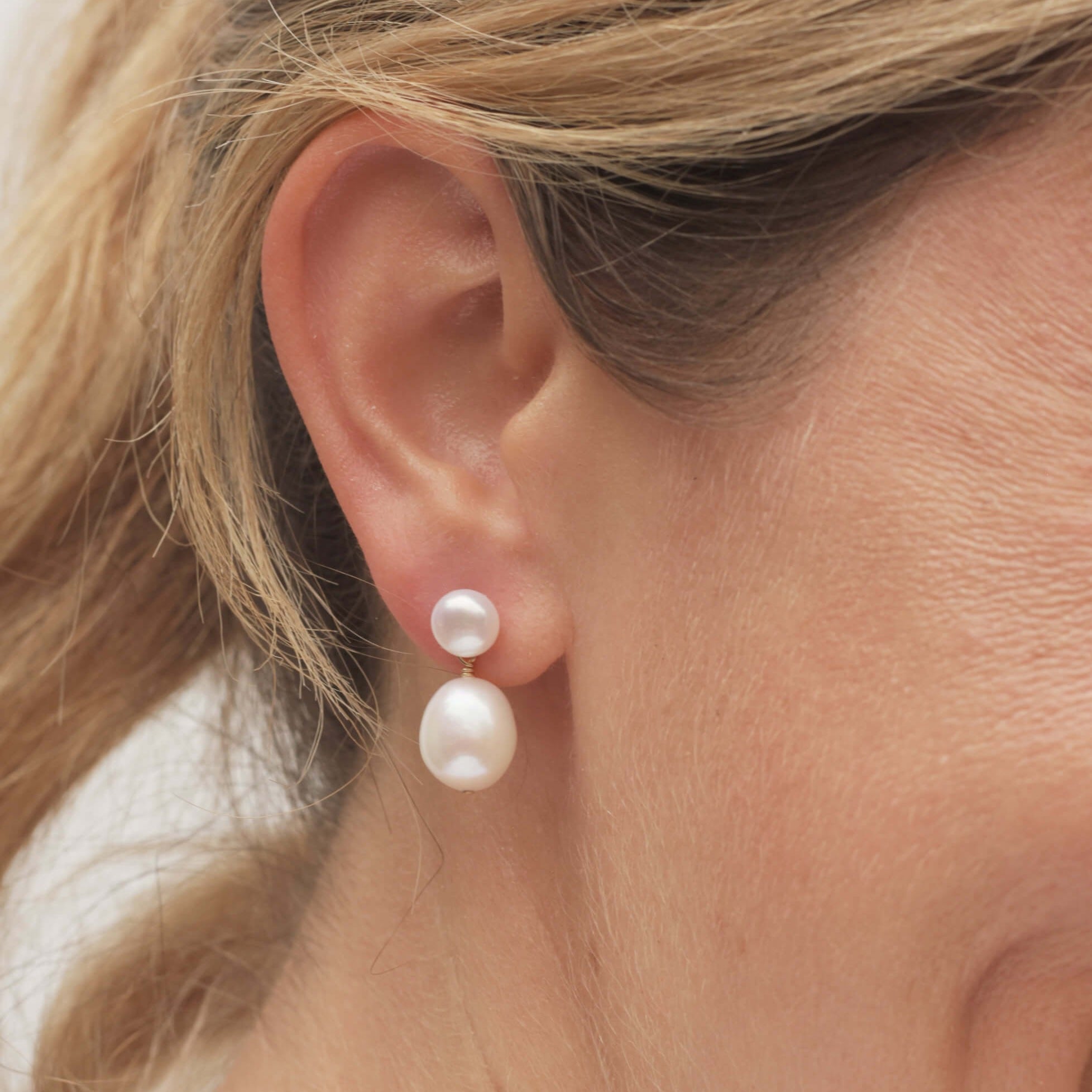 Closeup of white pearl drop earring on model