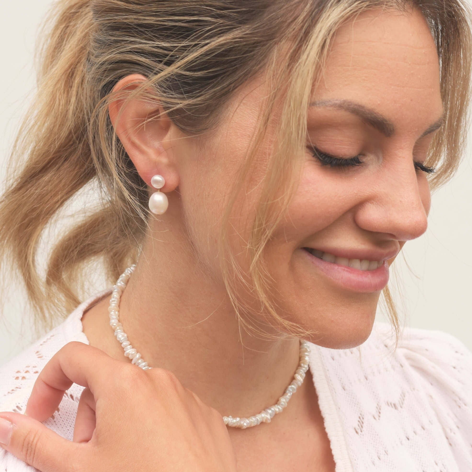 Close up of blonde model wearing pearl drop earrings and irregular pearl necklace