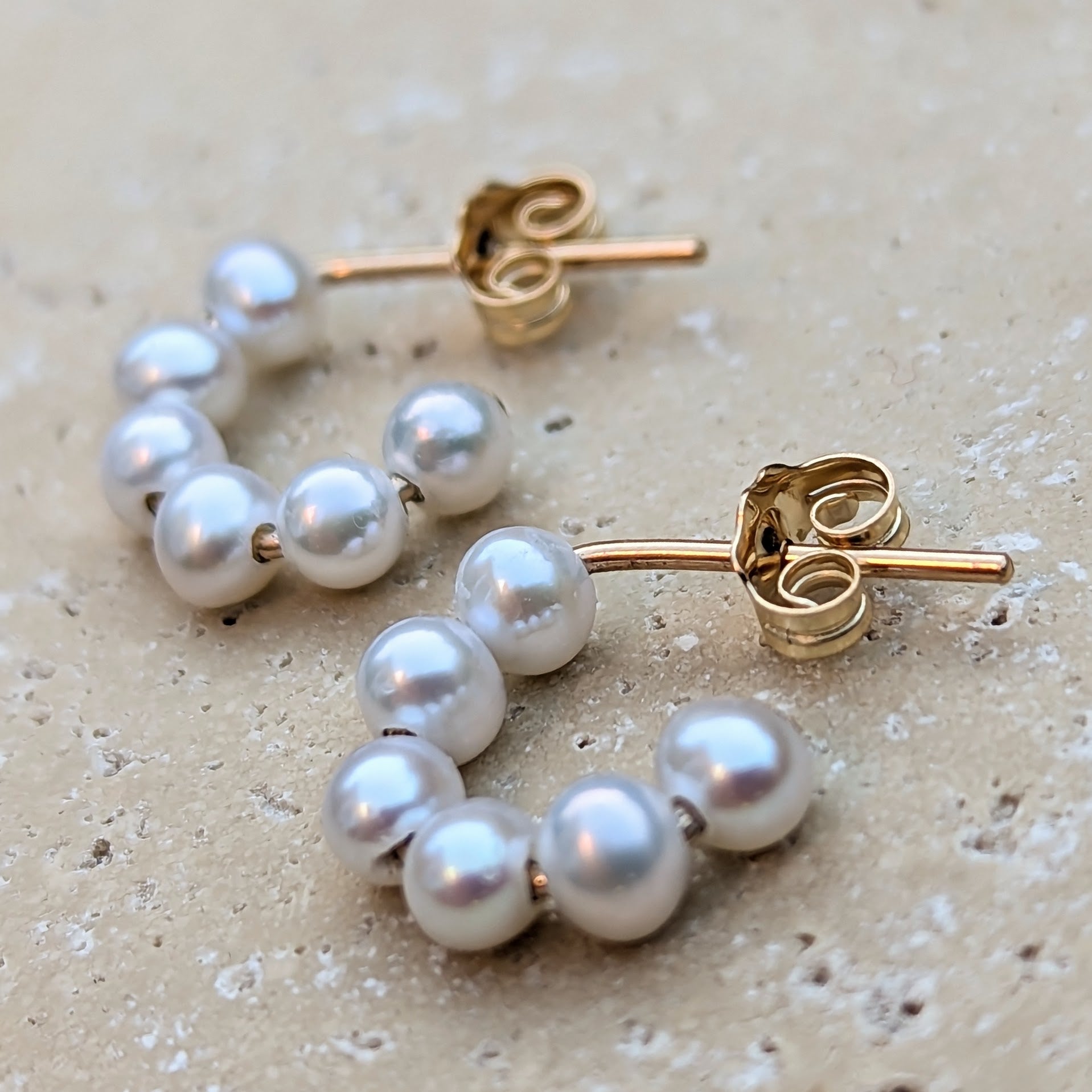 Close up of semi hoop pearl earrings in gold