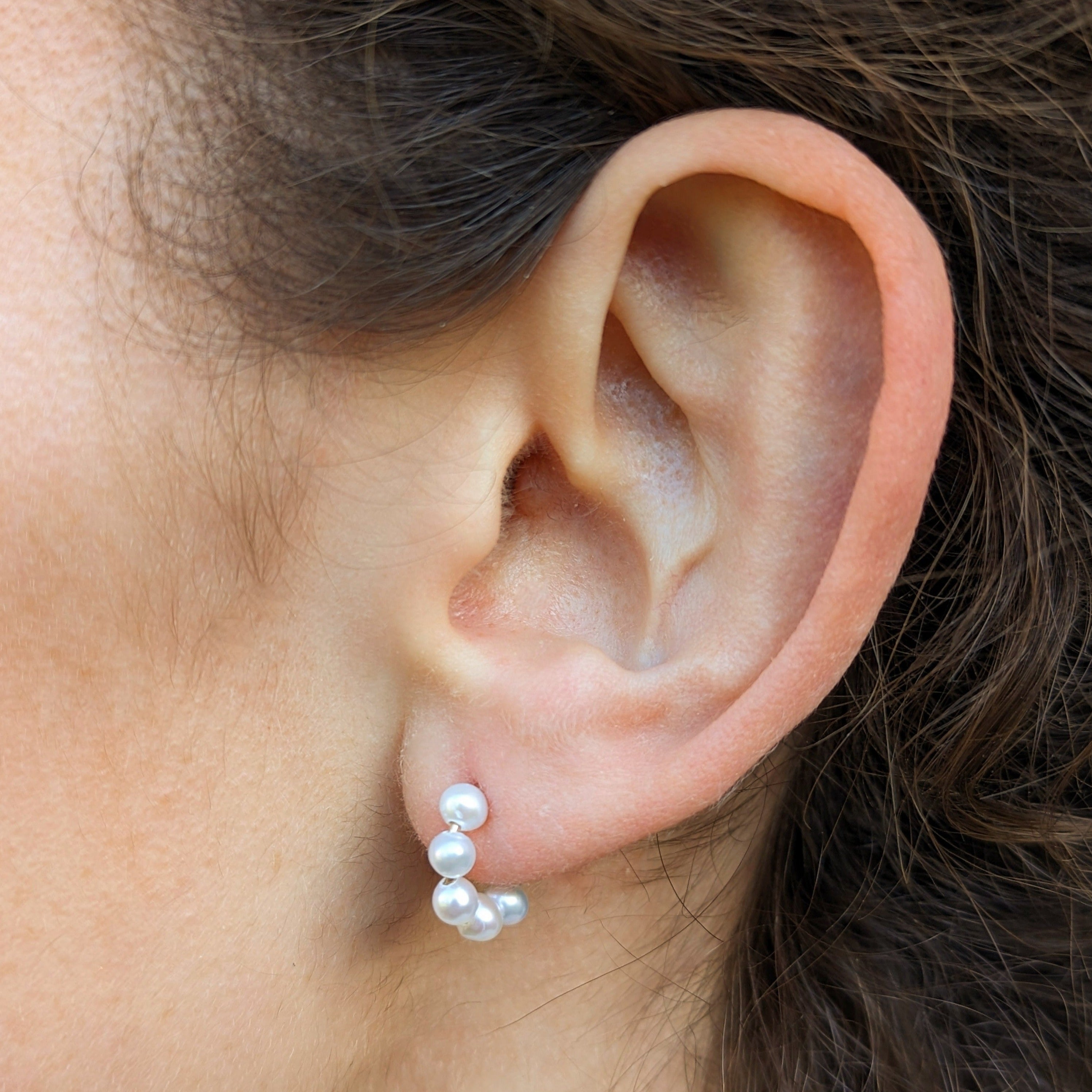 Close up of model wearing pearl hoop earrings
