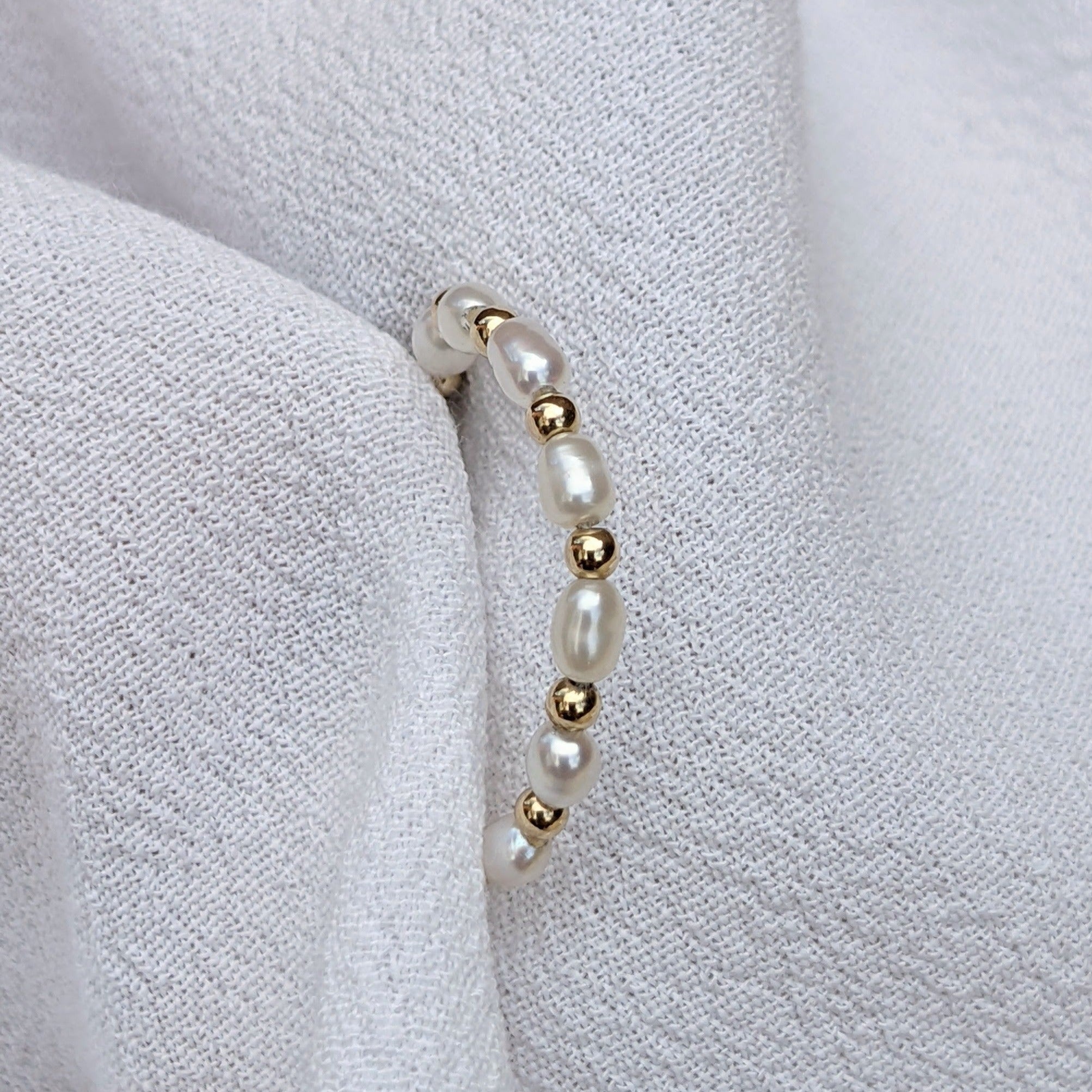 Seed pearl and gold bead ring held in white fabric