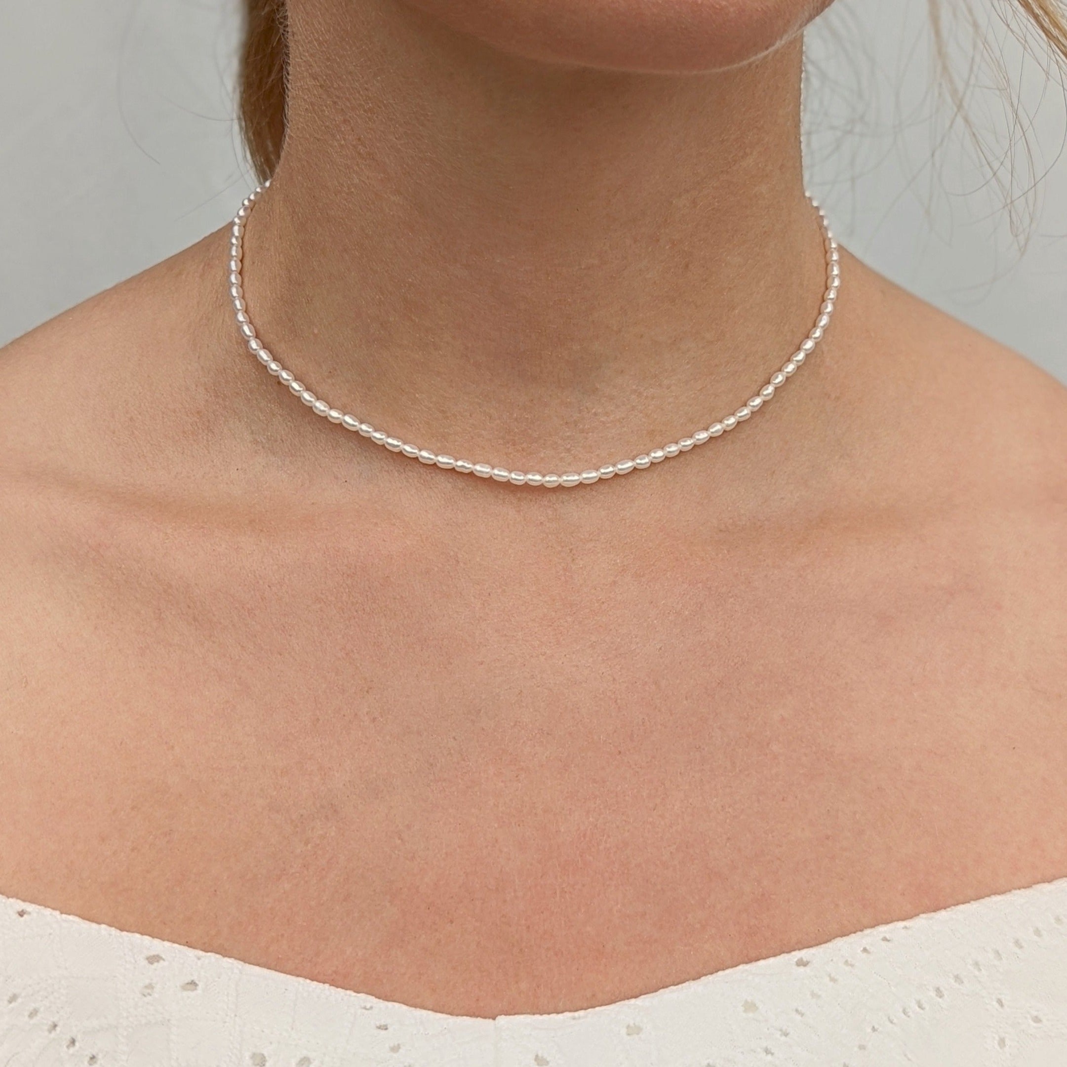 Close up of neck and seed pearl necklace