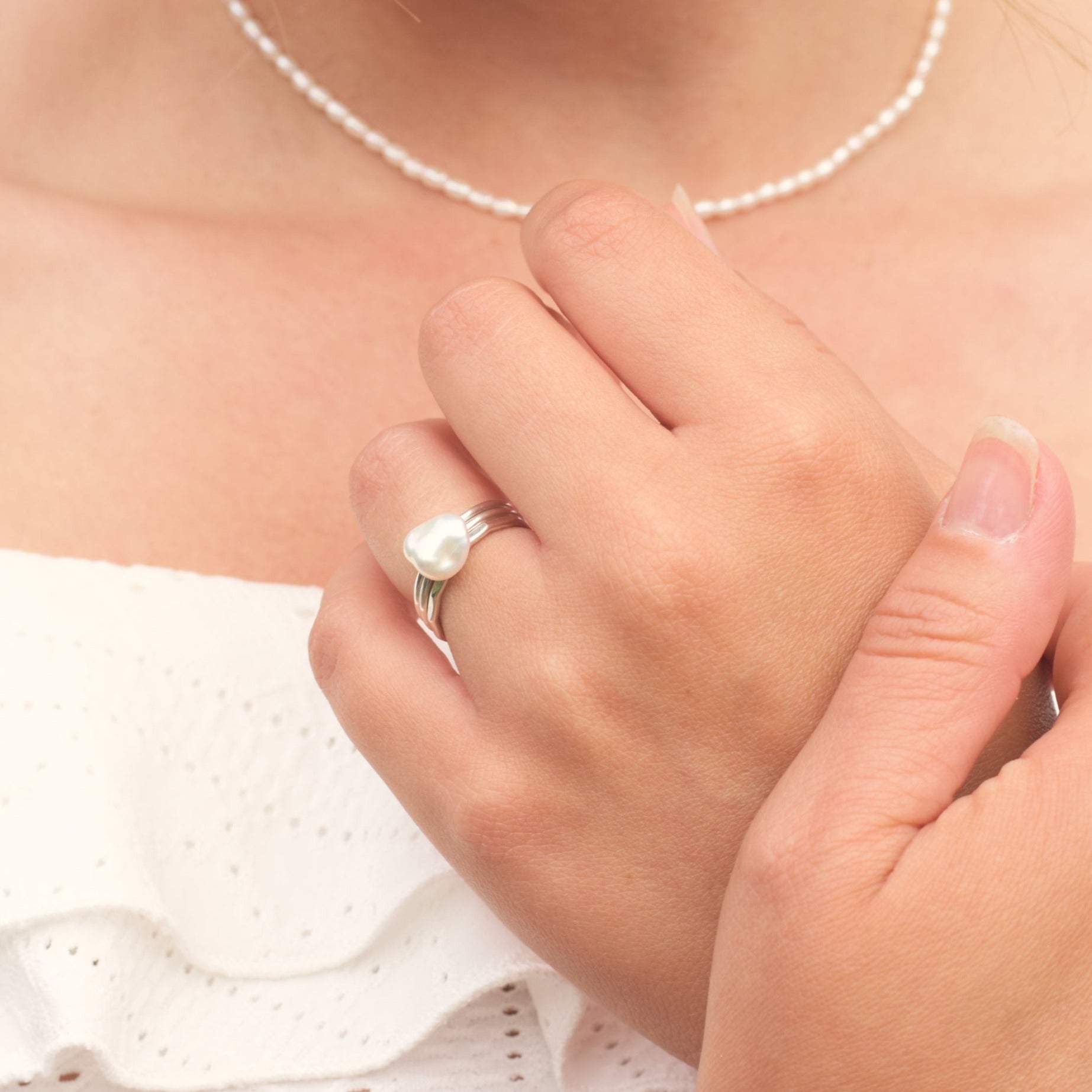 Model holding hands together wearing stack of silver rings