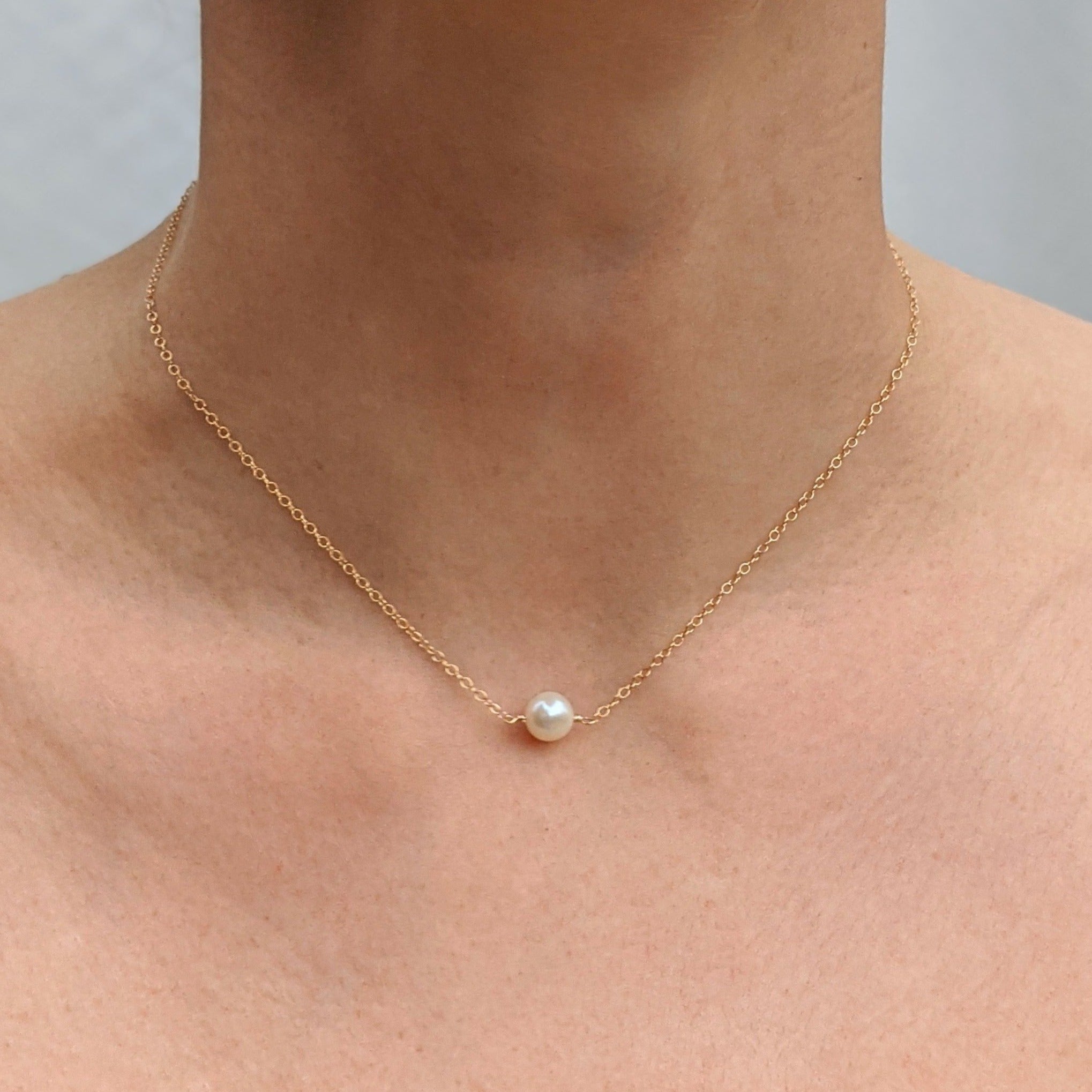 Single round pearl necklace gold on model