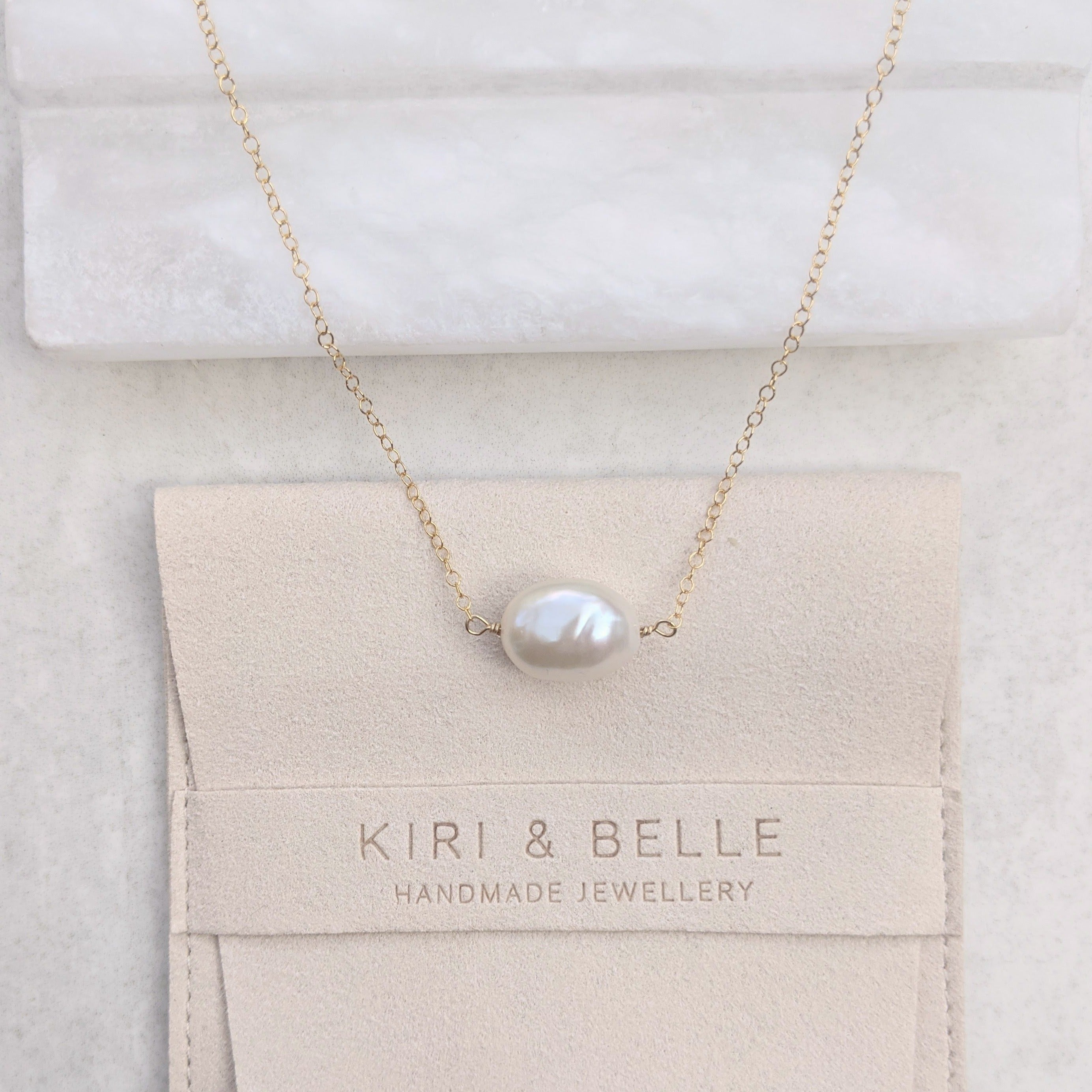 Single horizontally strung large baroque pearl on a fine gold chain necklace