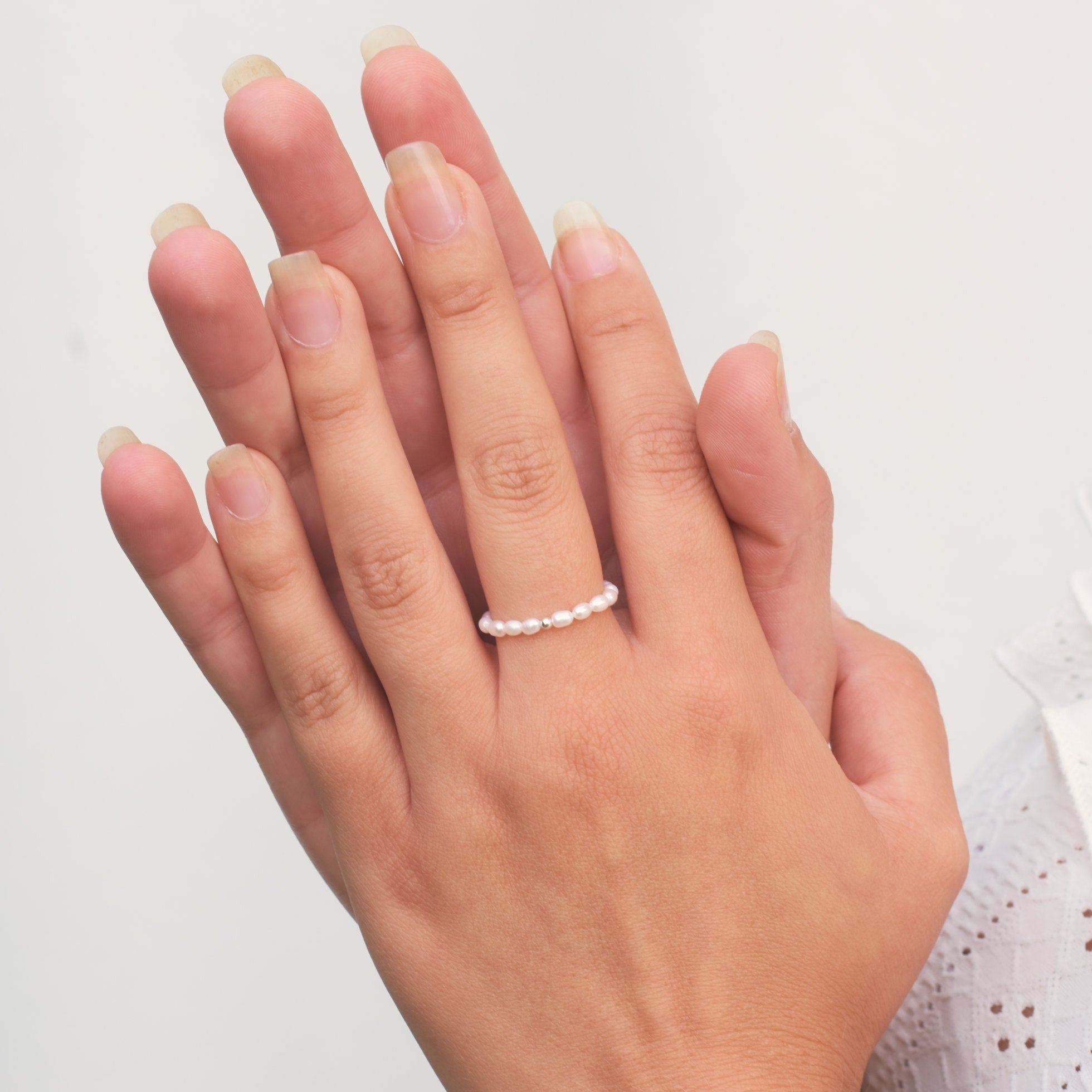 Hands together wearing a mini pearl ring