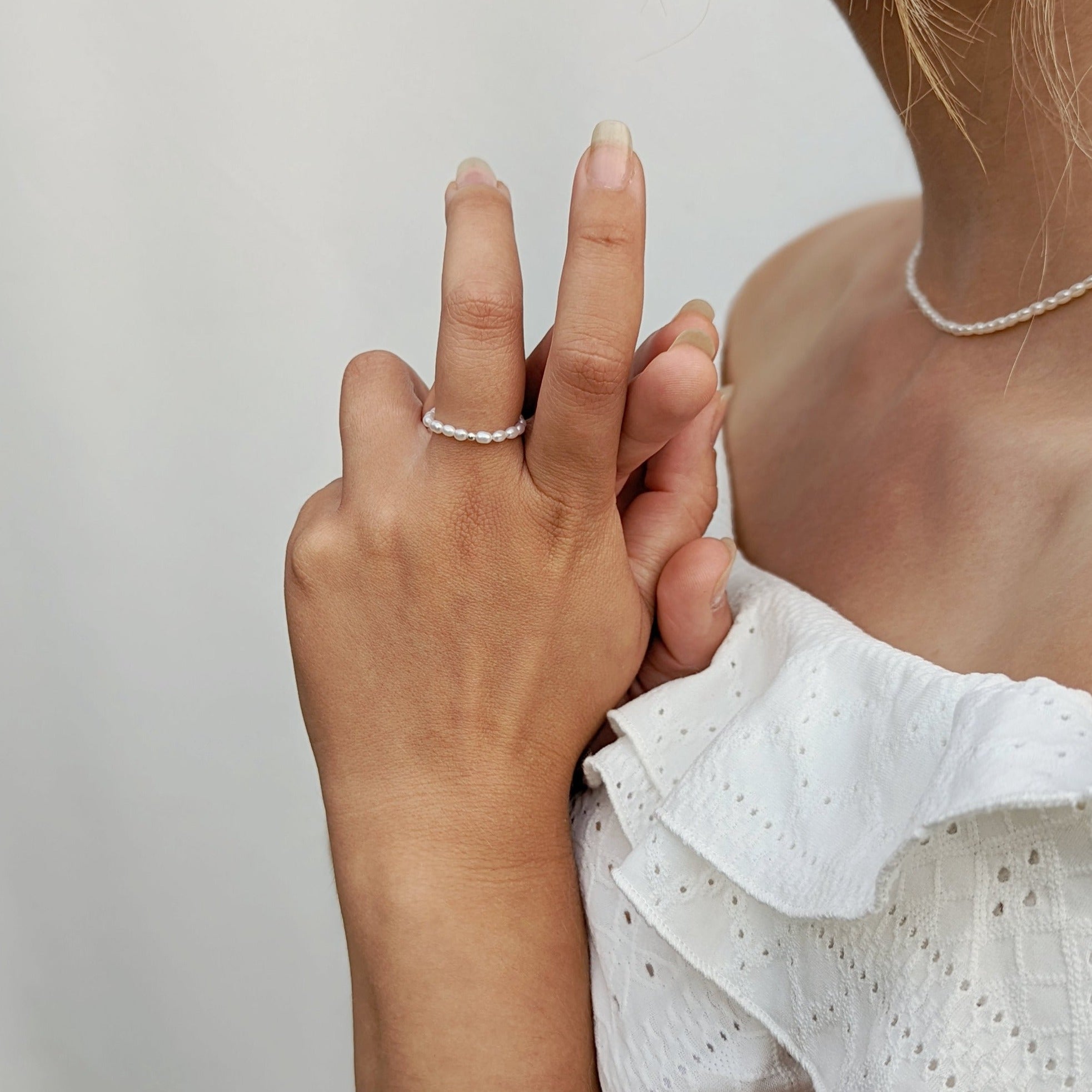 Model wearing pearl necklace and ring