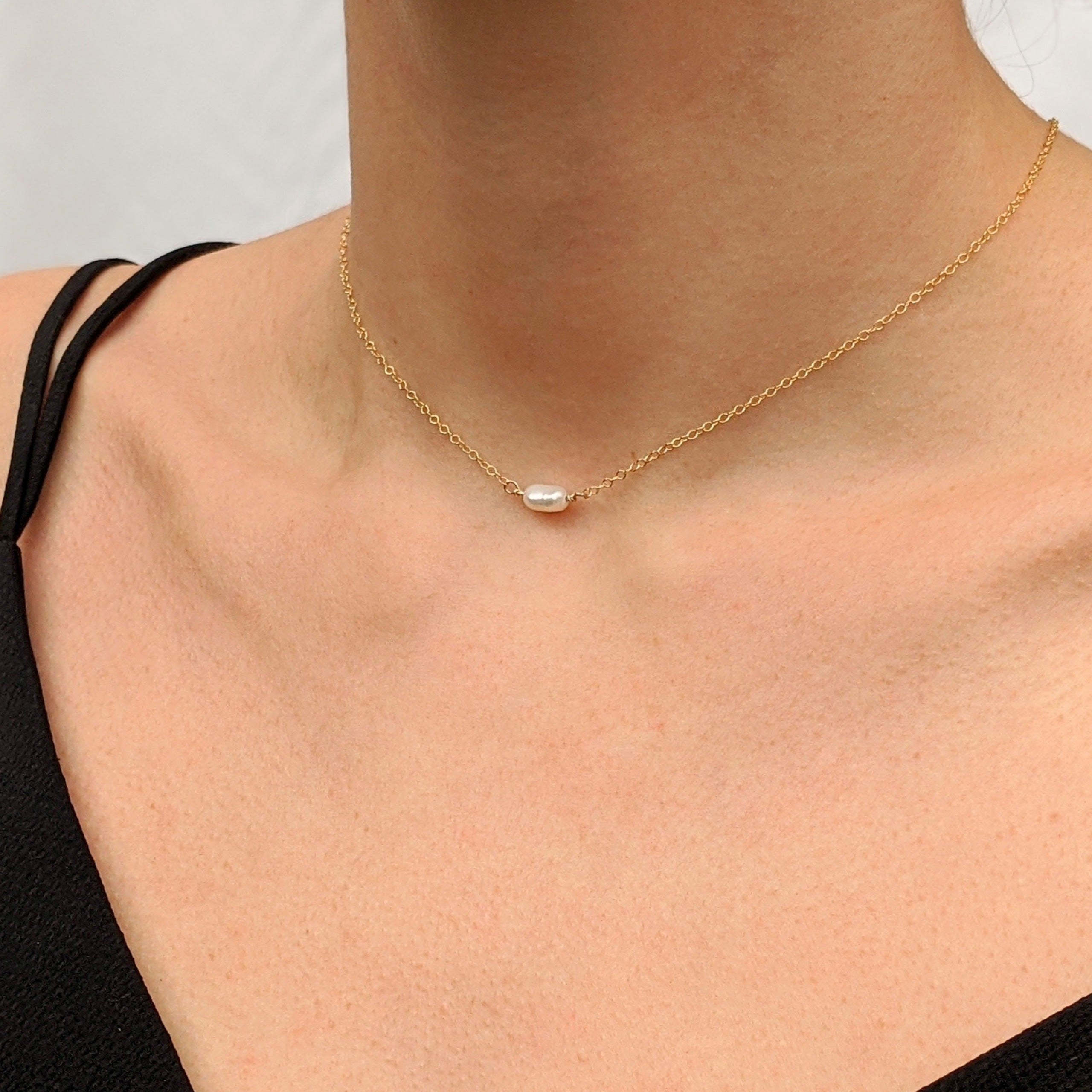 Single small pearl choker necklace in gold on model neck