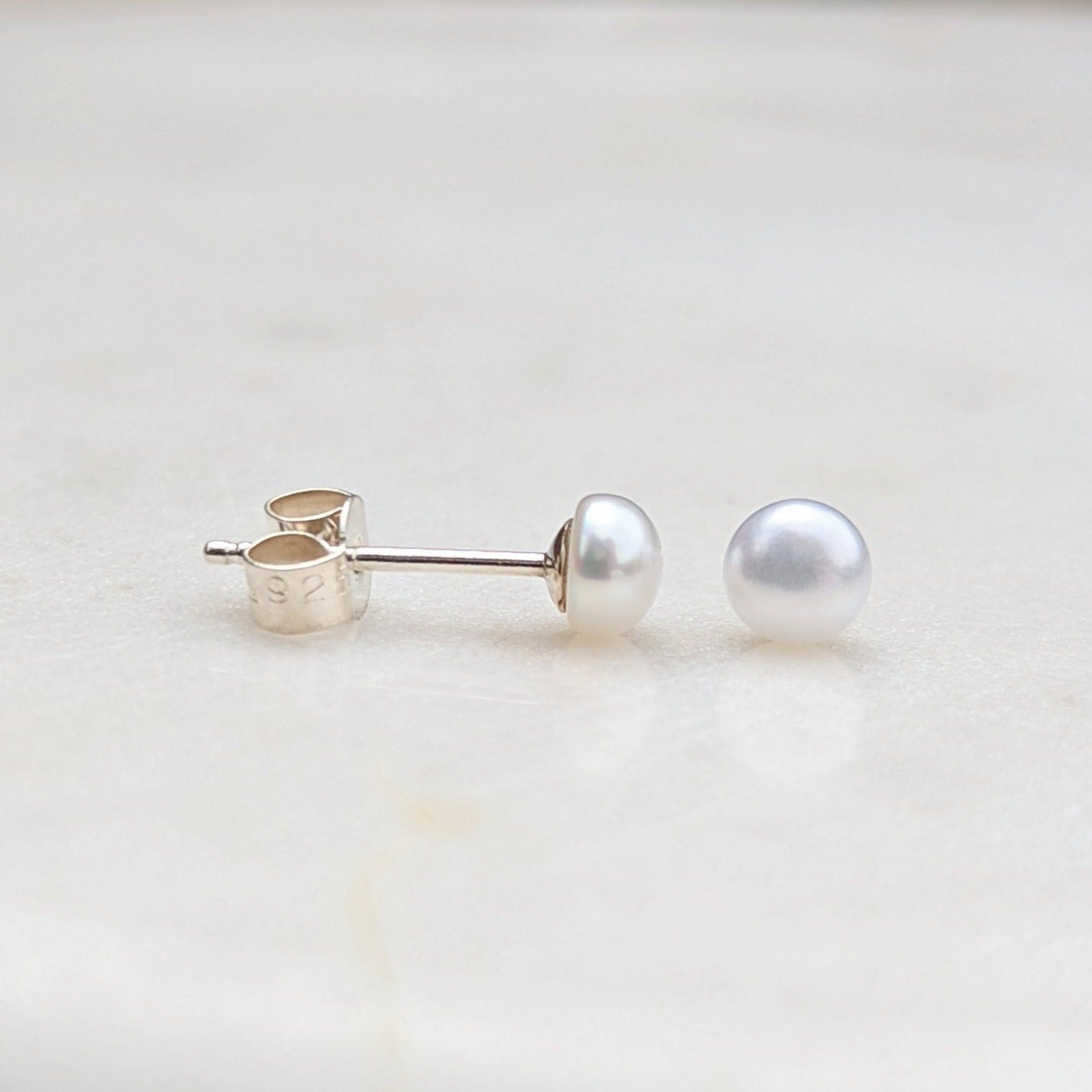 A pair of silver small button pearl stud earrings