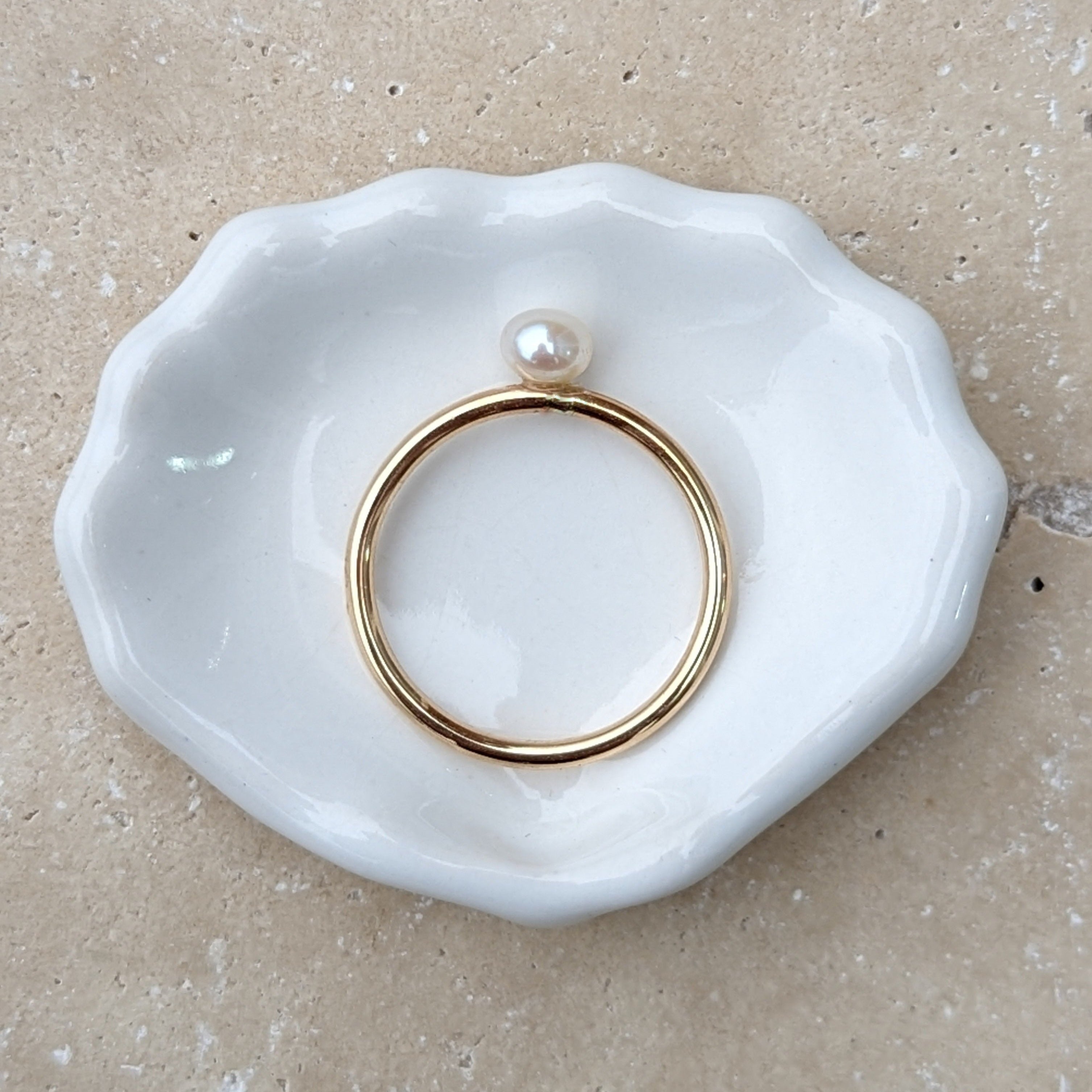 Small round pearl gold ring laid flat
