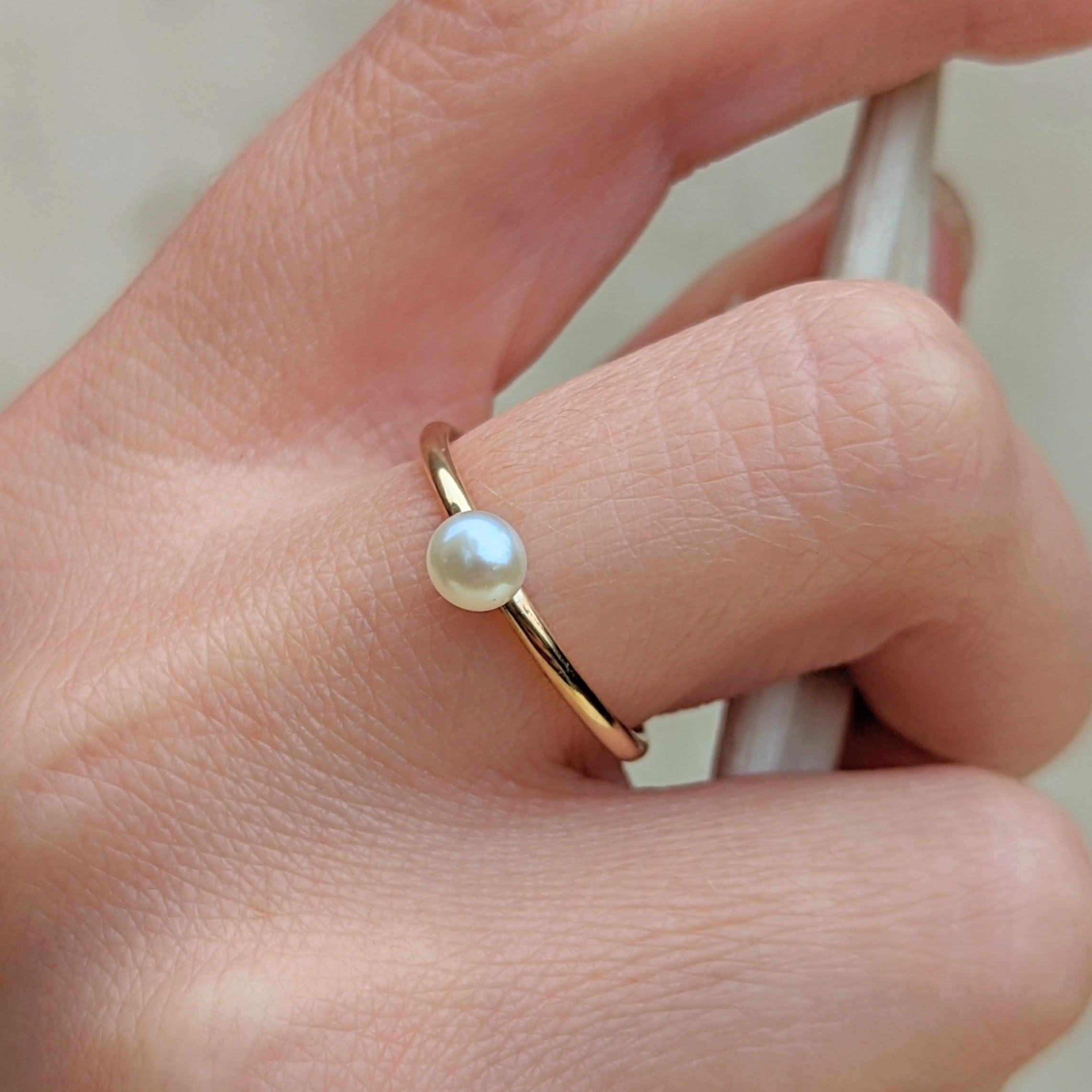 Closeup of hand holding branch and wearing a small pearl gold ring