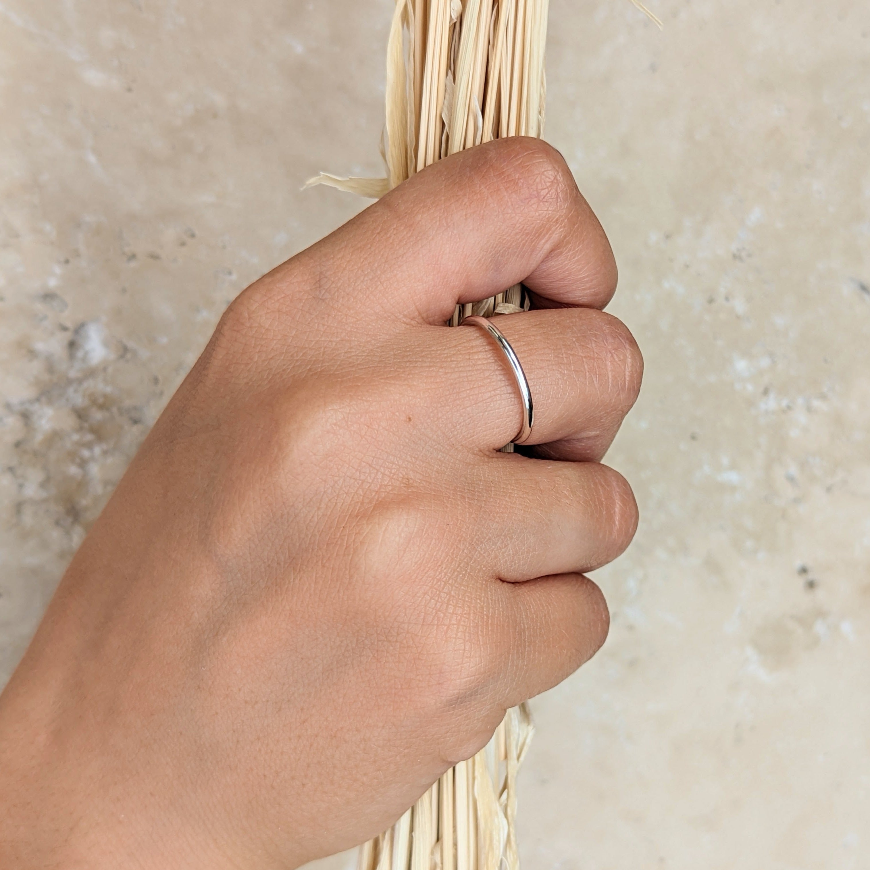 hand holding dried grass and wearing a single thin silver ring