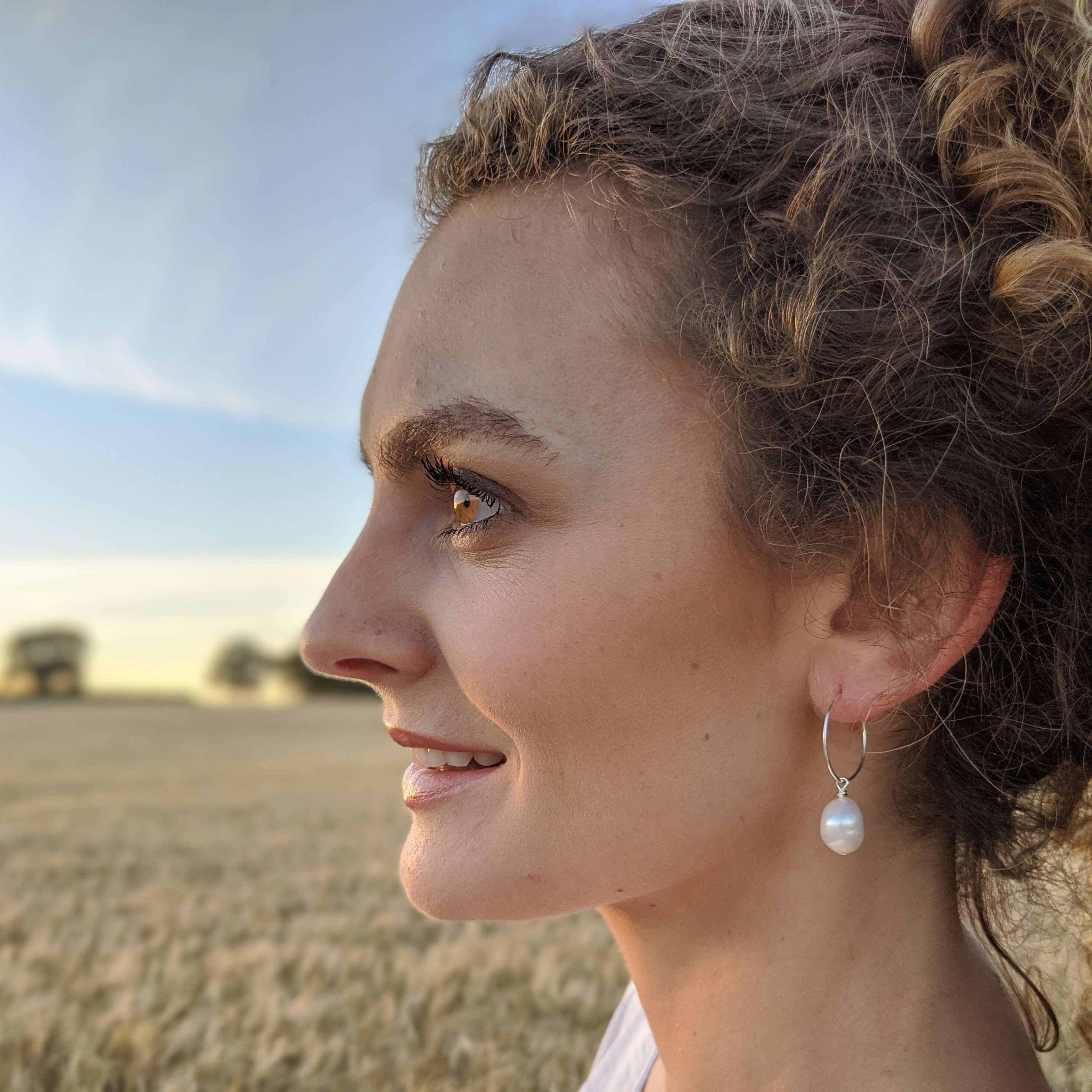 thin hoop pearl earrings on model side view