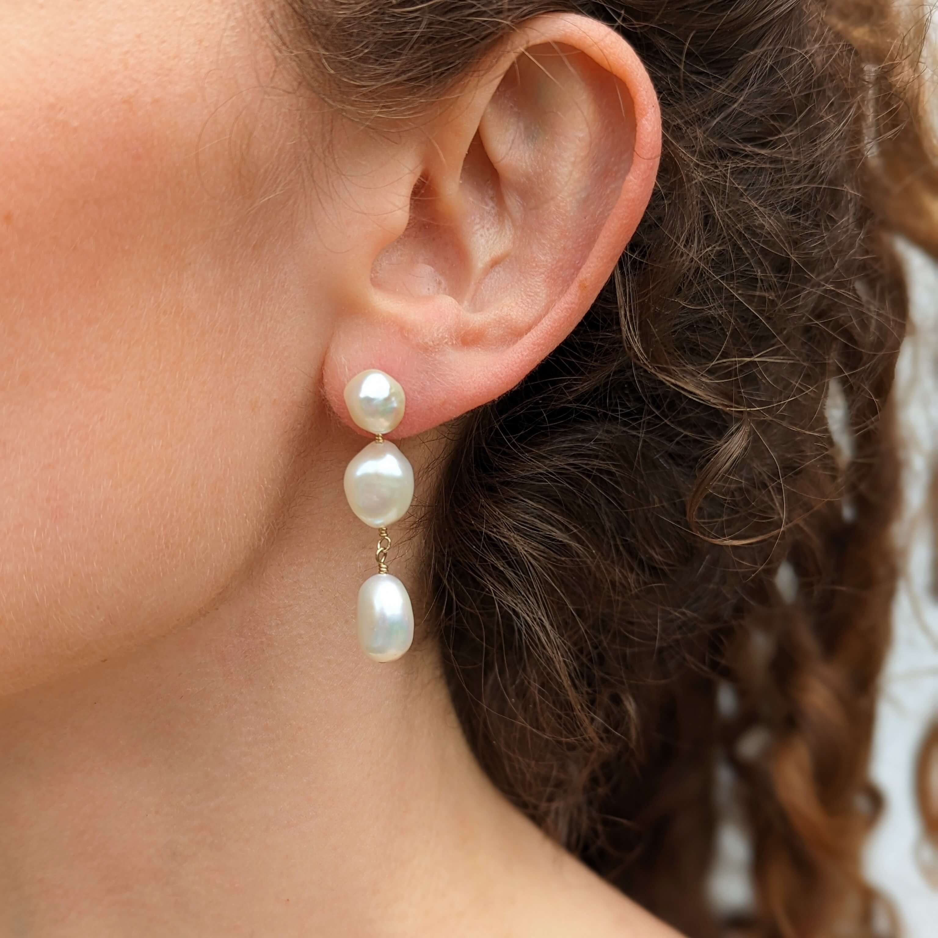 Model wearring three pearl drop earrings