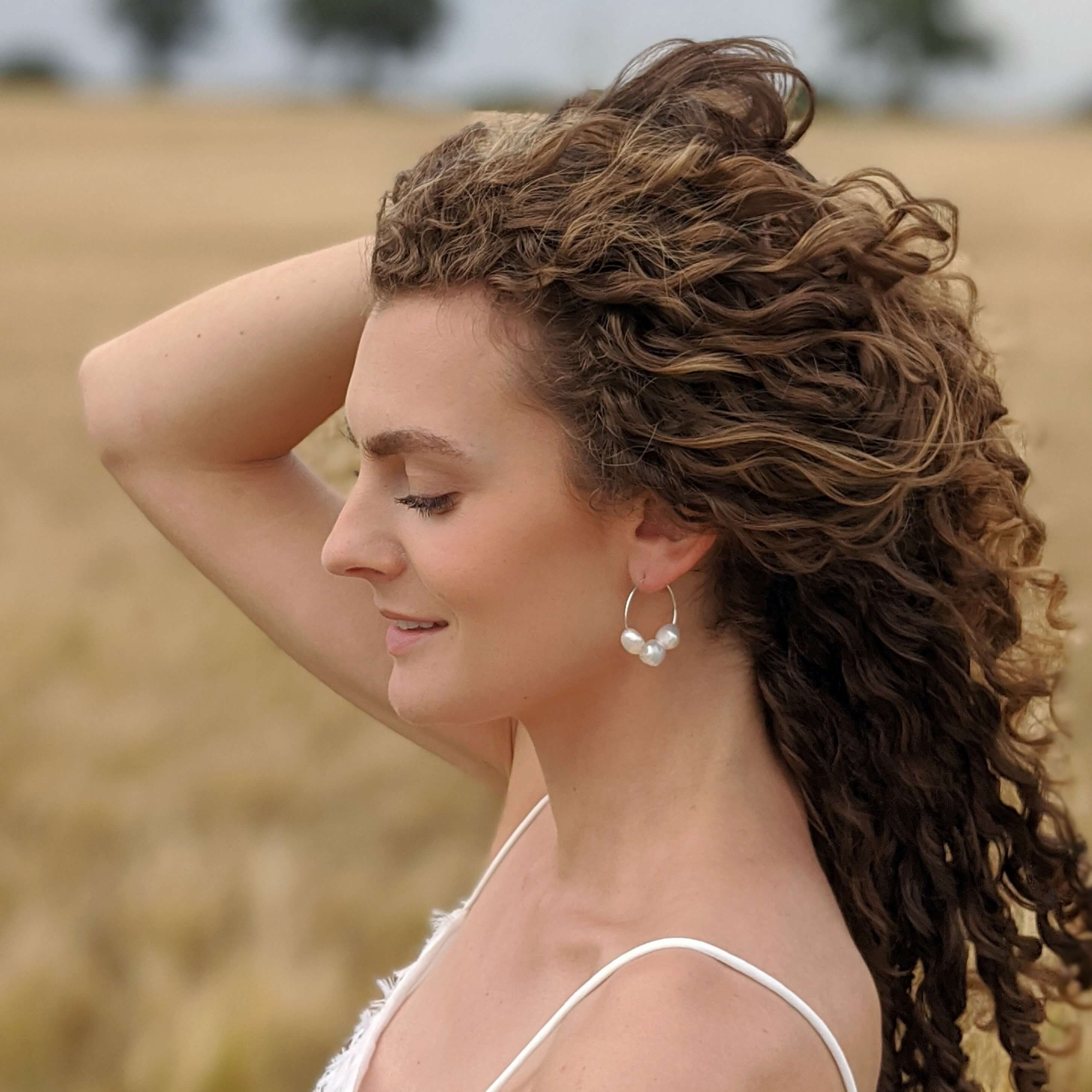 Curly hair model with pearl wire hoop earrings